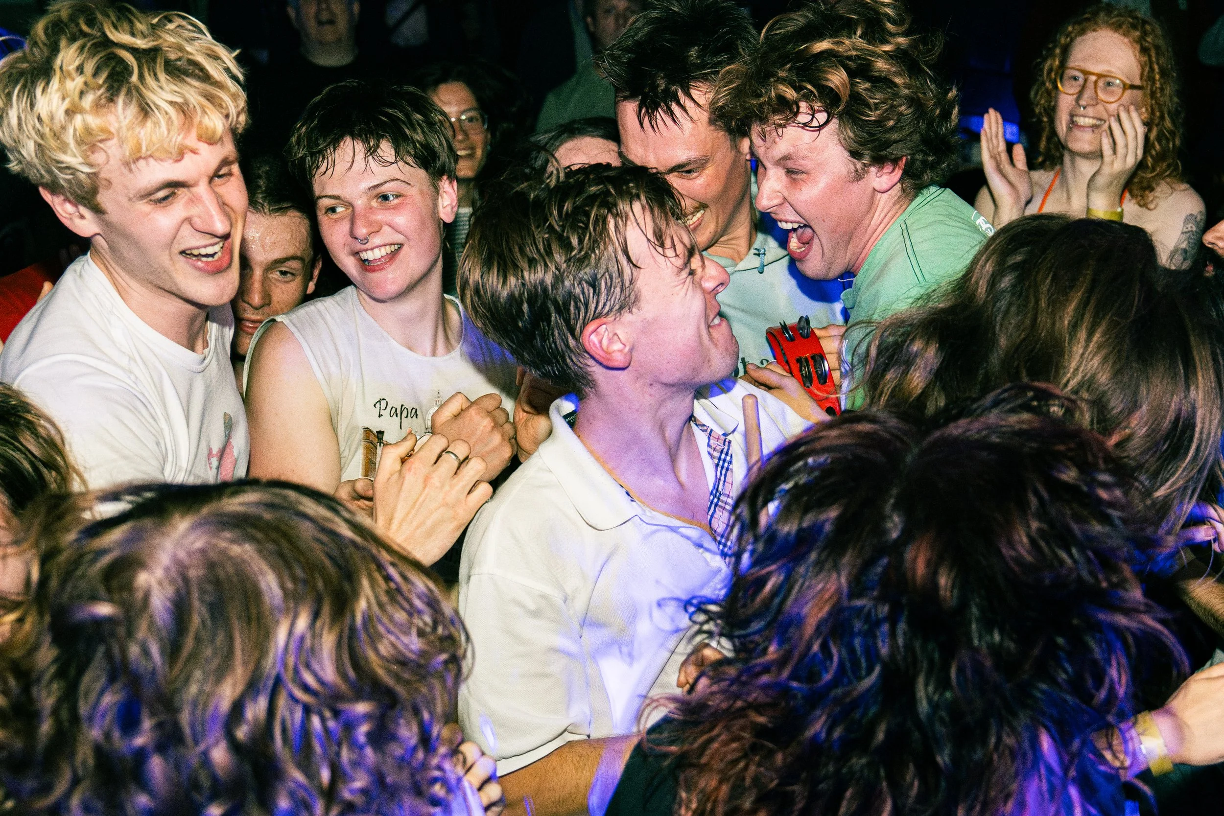 Group of people, mostly young adults, celebrating and laughing closely together at a lively event or party.