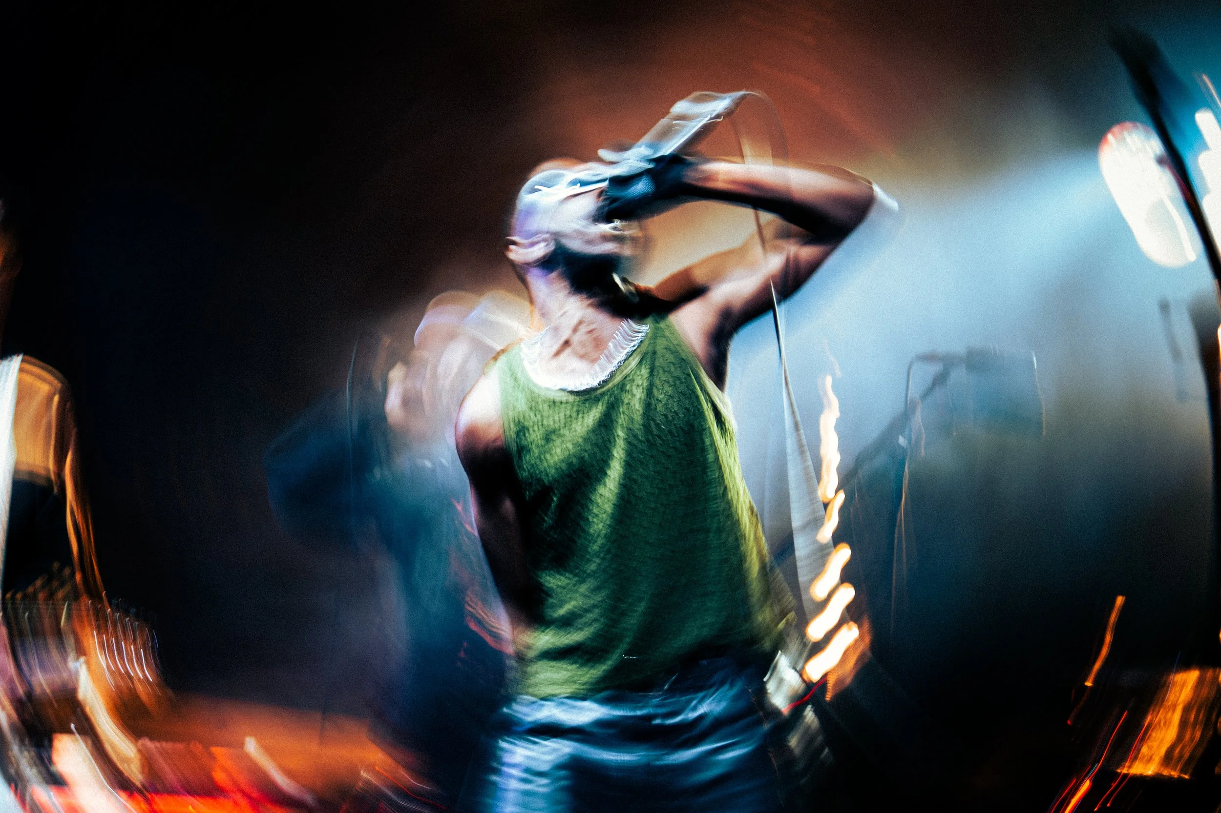 A woman singing into a microphone on stage with colorful lights in a blurry motion shot.