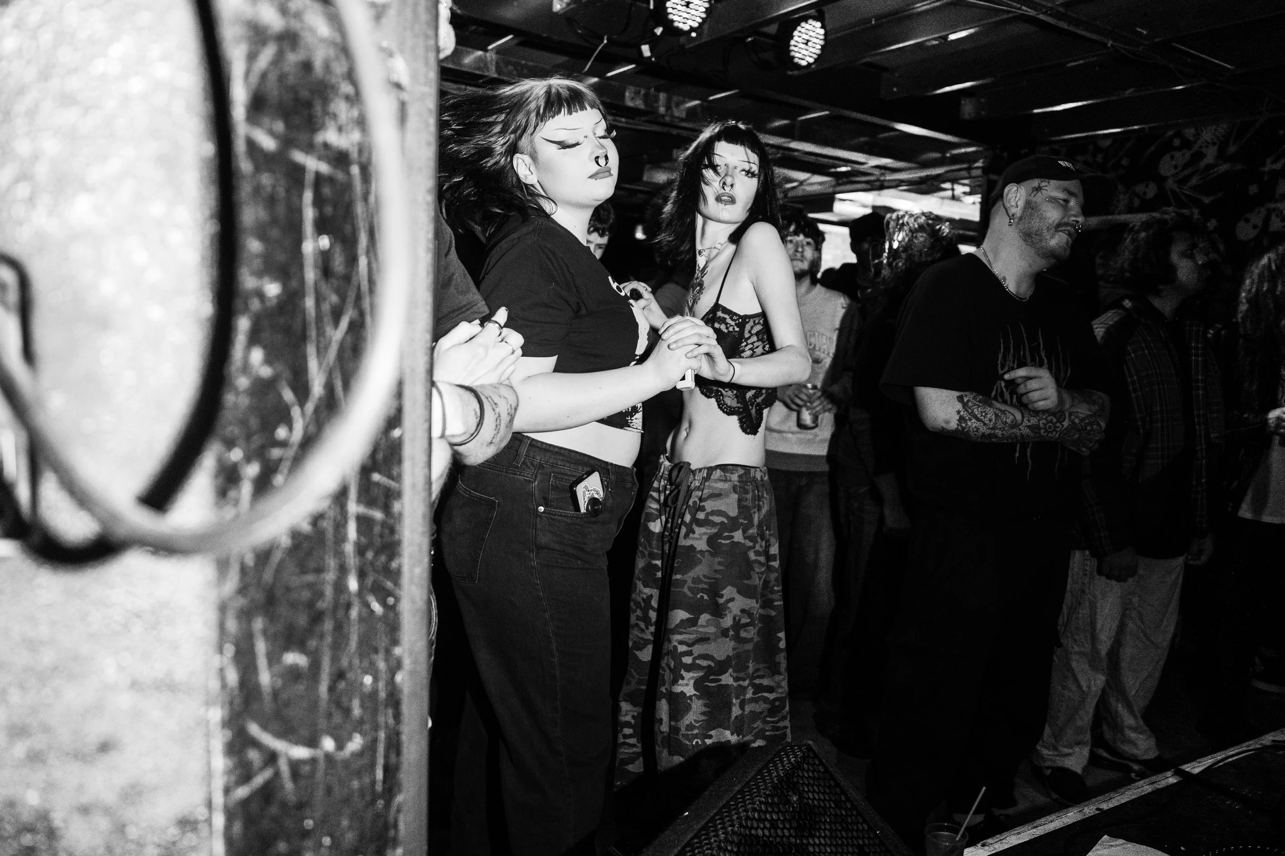 People dancing in a dark, lively music venue with a graffiti-decorated ceiling, dressed in casual and alternative fashion.