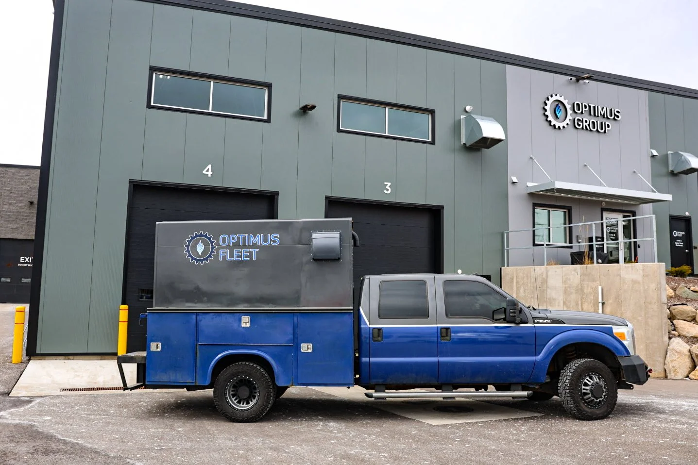 Mechanic jump-starting a truck with jumper cables at Optimus Group fleet repair in Walker, MI.