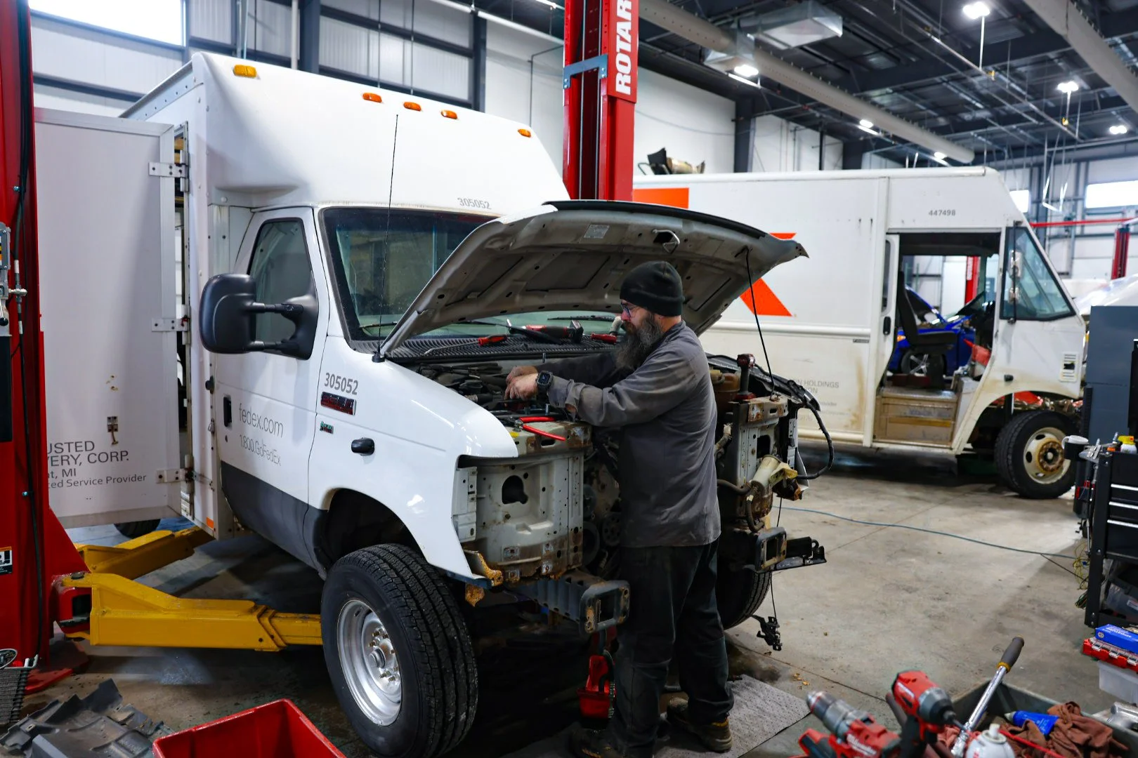 Fleet mechanic inspecting semi-truck and recording notes at Optimus Group in West Michigan.