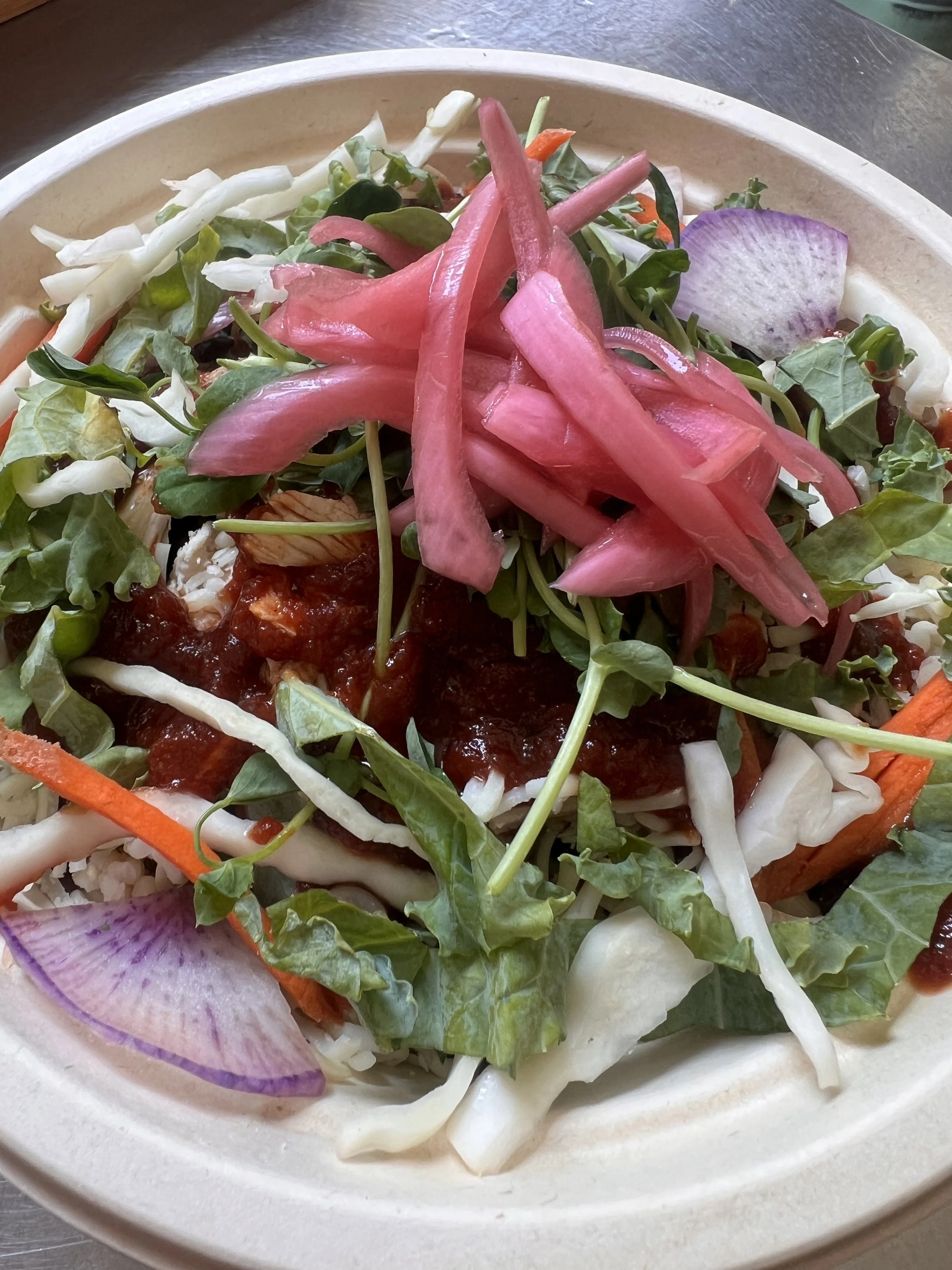 Grain bowl topped with pickled onions, purple radish, cabbage, kale and carrots
