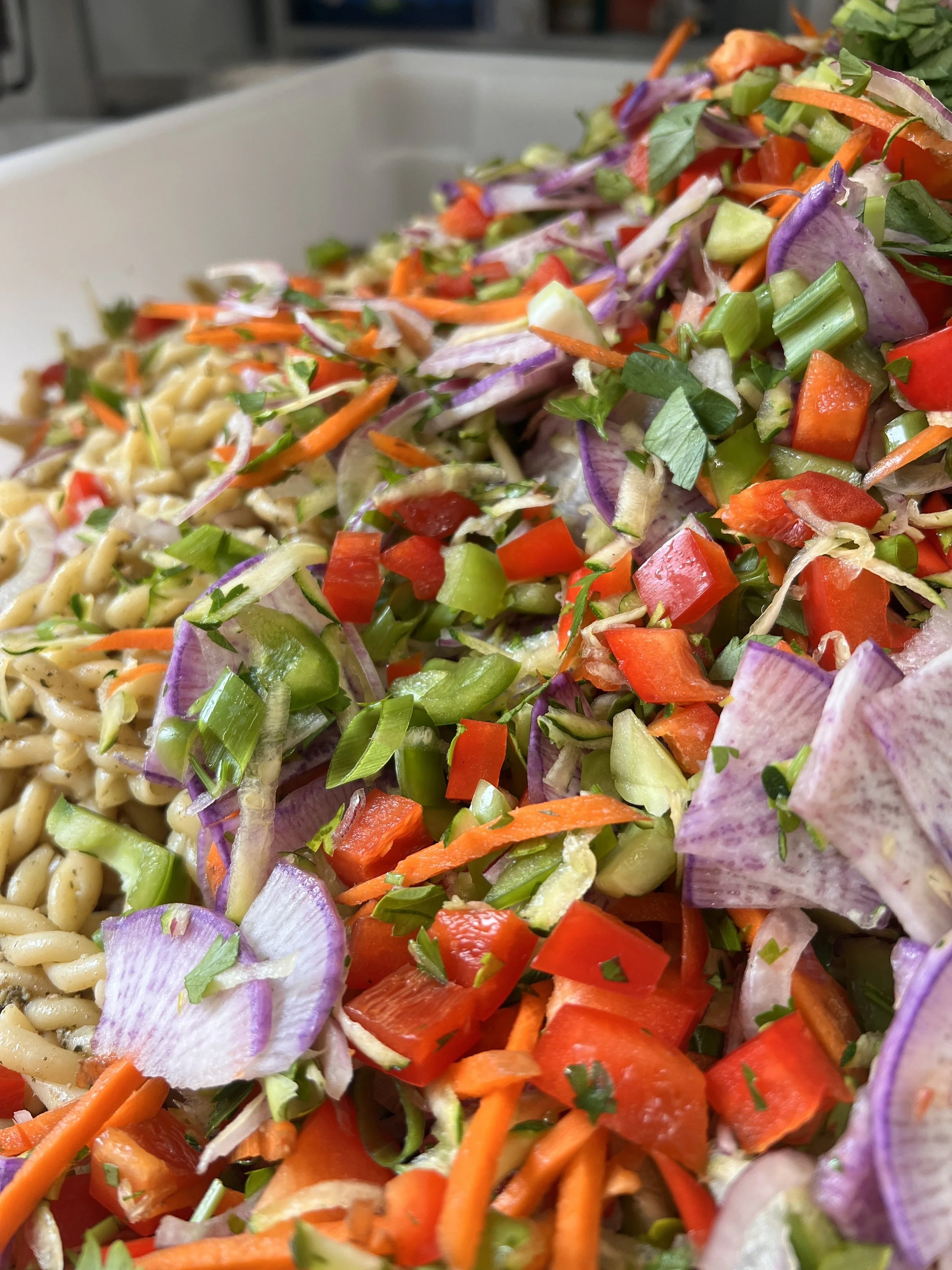 A rainbow of chopped veggies atop pesto pasta