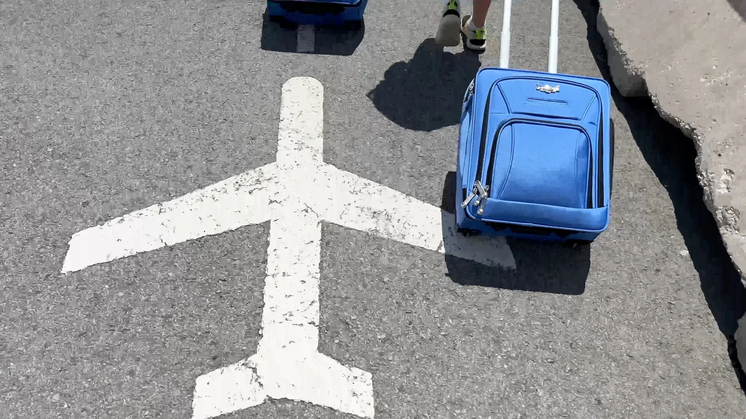 Carry-on suitcase rolled next to painted airplane on the ground