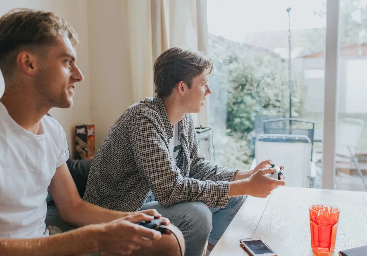Ben and a friend sitting together playing video games.