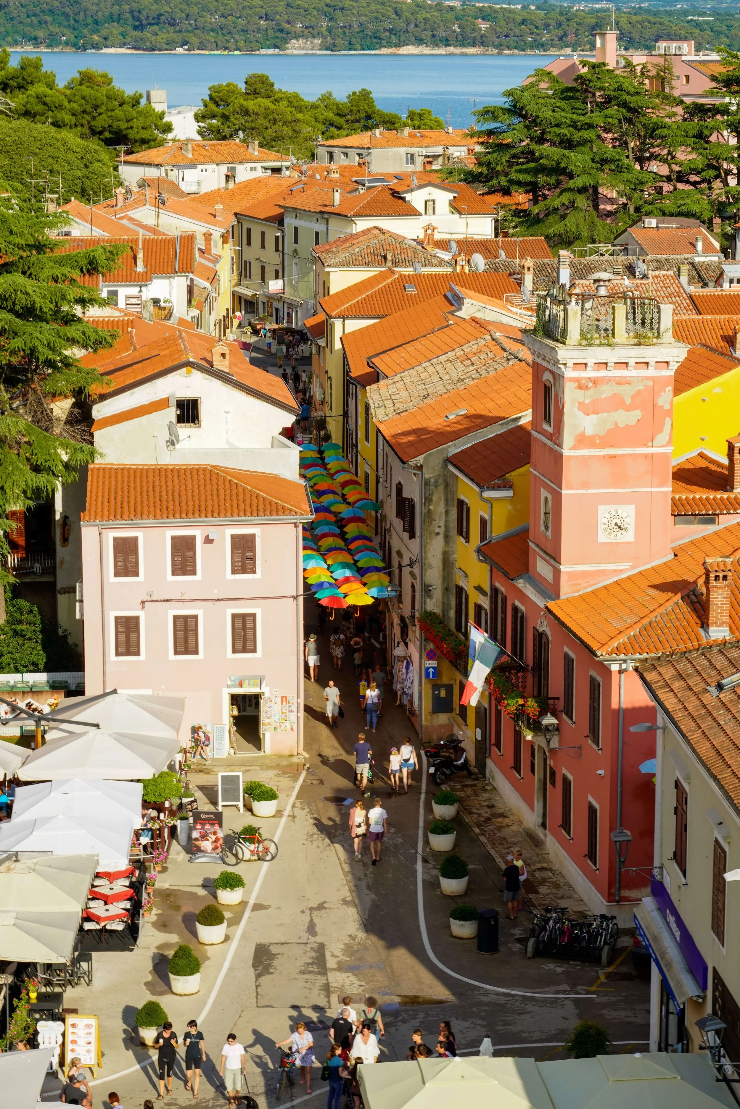 Novigrad, Istria, Croatia, featuring a colorful cobblestone street lined with pastel buildings and terracotta rooftops, with the bell tower of St. Pelagia Church rising in the background.