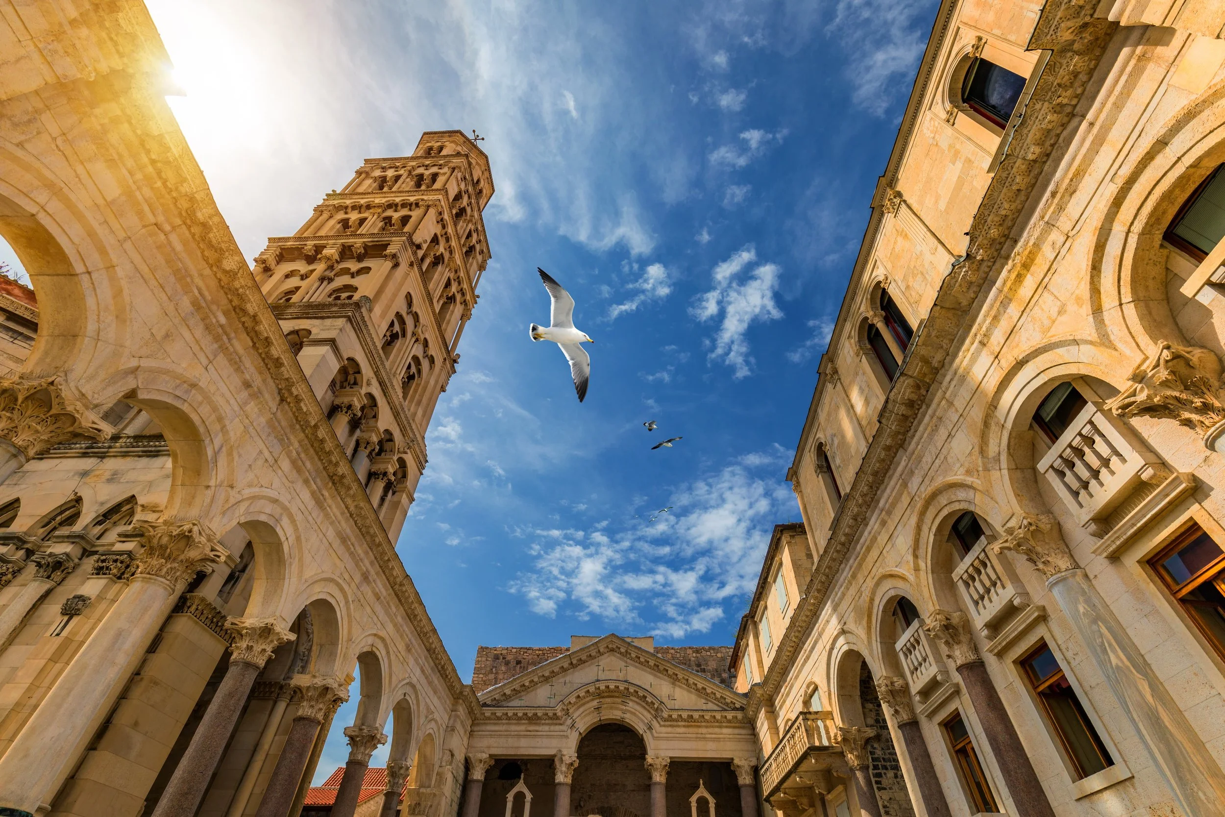 Peristyle courtyard of Diocletian’s Palace, featuring ancient Roman architecture and the bell tower of the Cathedral of Saint Domnius in Split, Croatia.