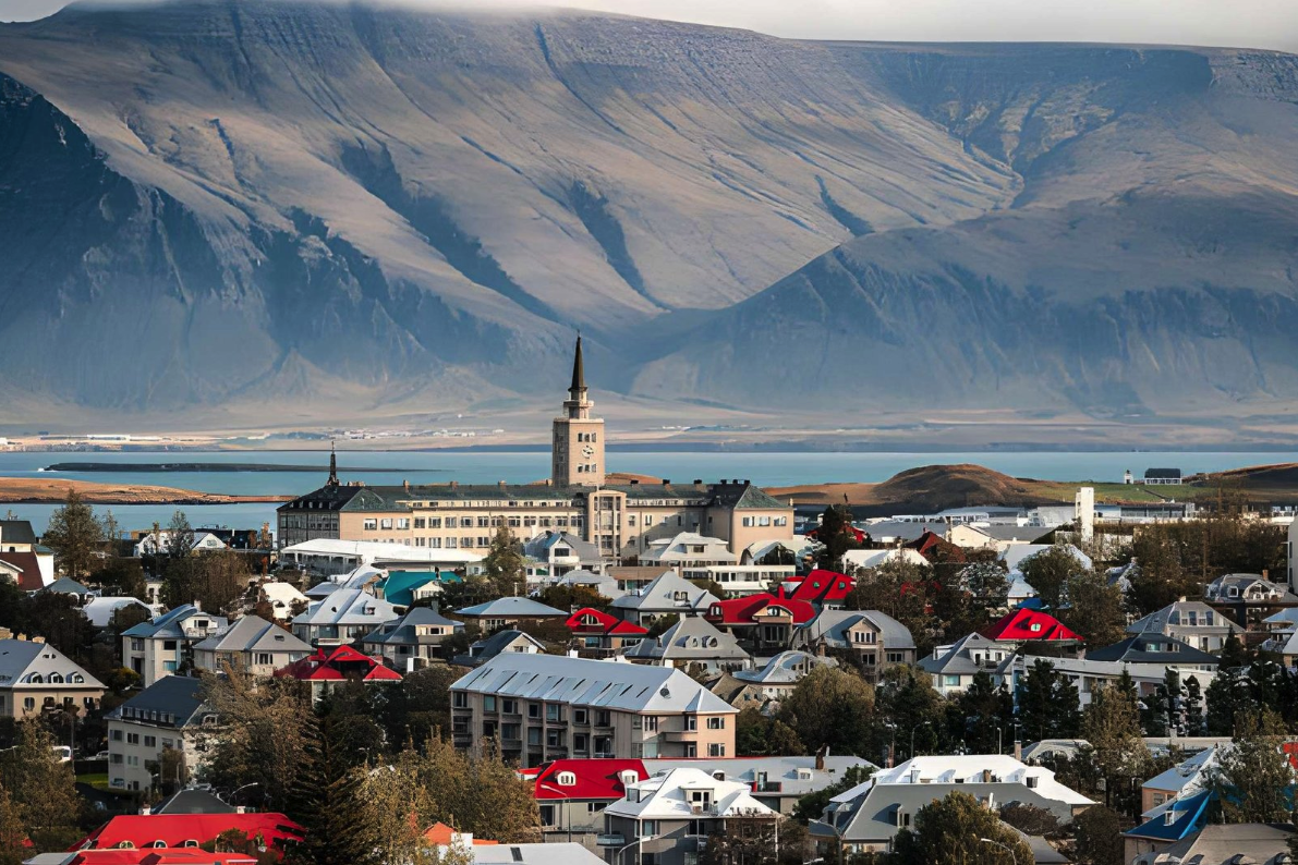 Panoramic view of Reykjavik city skyline in Iceland with colorful rooftops, historical architecture, and Mount Esja in the background across the bay.