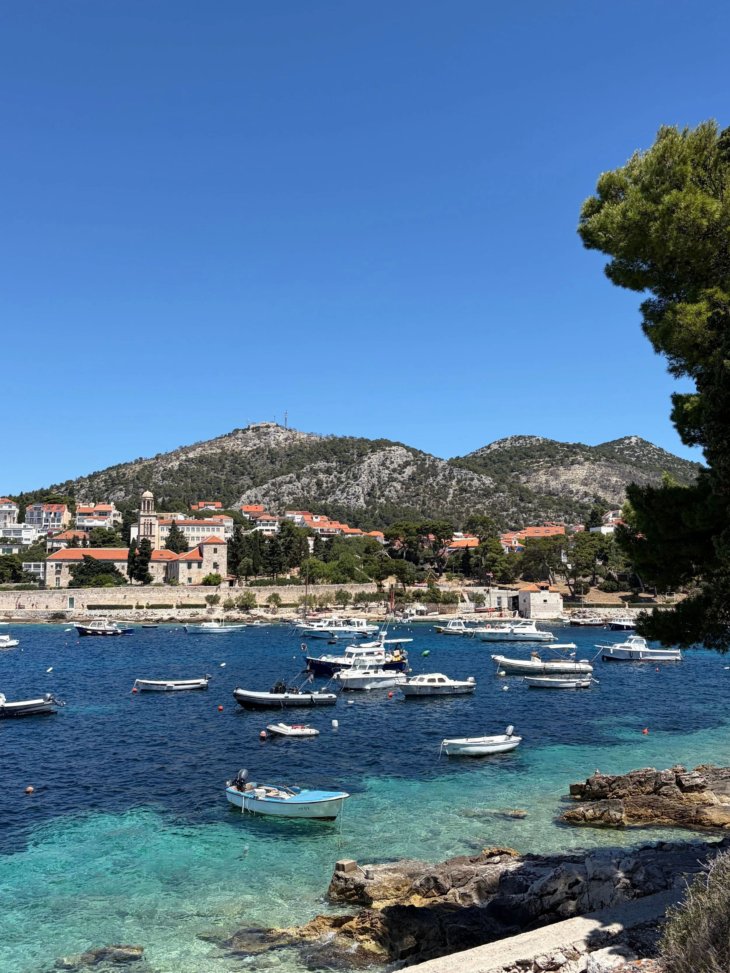 Komiža, Split-Dalmatia County, Croatia, featuring a picturesque harbor with boats and a charming coastal town nestled beneath surrounding hills.