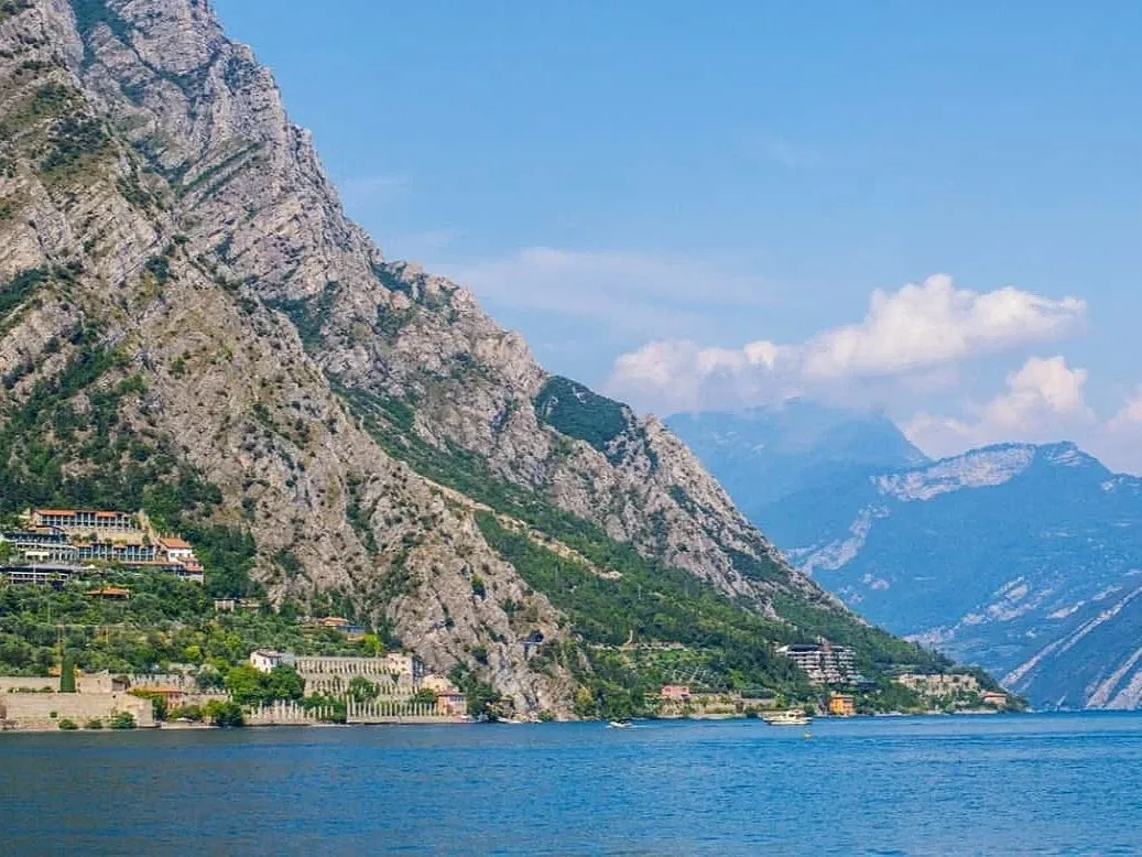 Riva del Garda, Trentino-South Tyrol, Italy, featuring scenic mountain views surrounding Lake Garda beneath a clear blue sky.