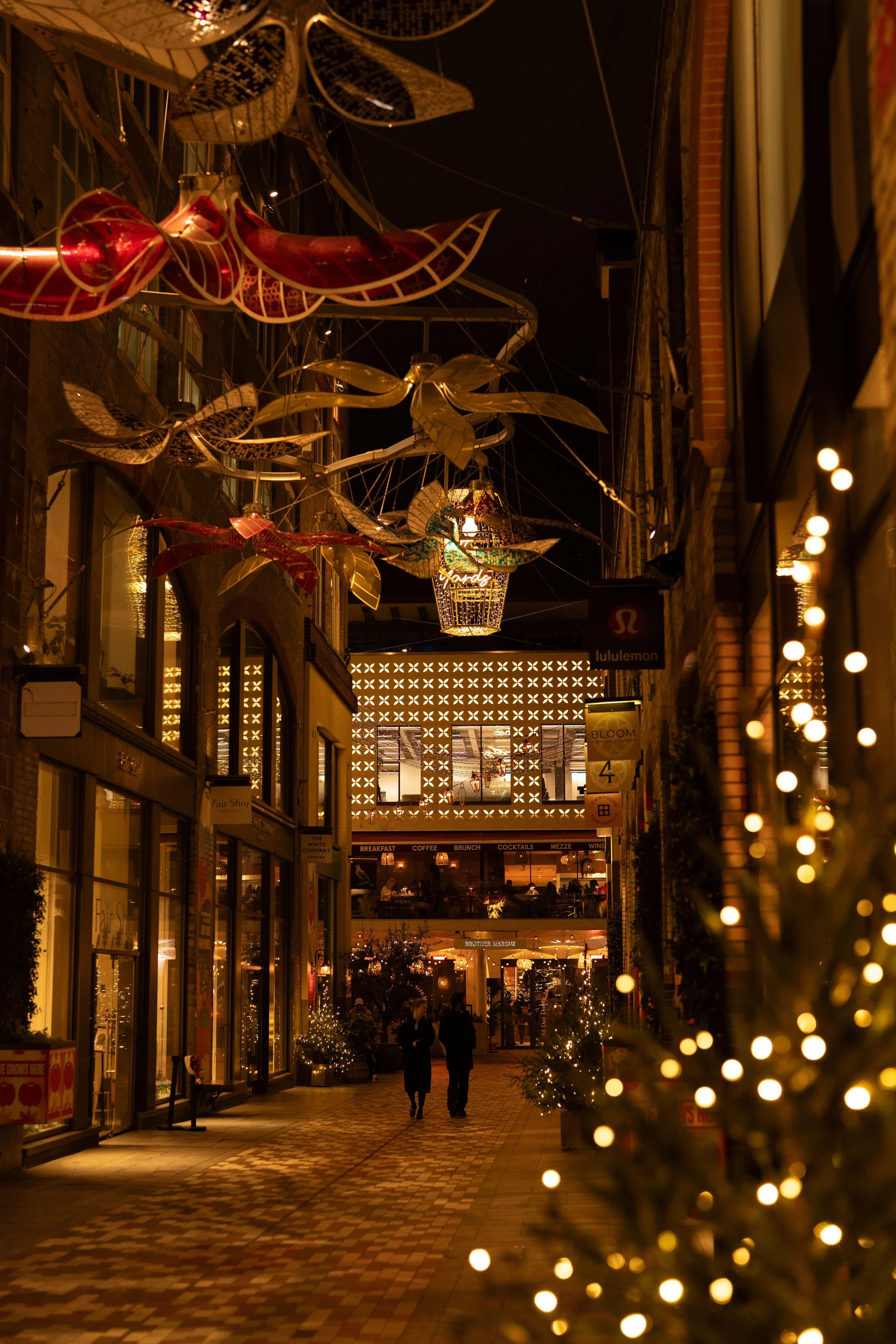 A beautifully decorated London street glowing with festive lights and holiday decorations at night.
