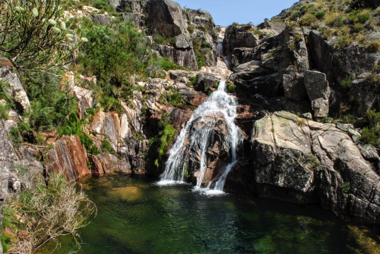 Mountain waterfall surrounded by lush greenery in Peneda-Gerês National Park, Portugal.