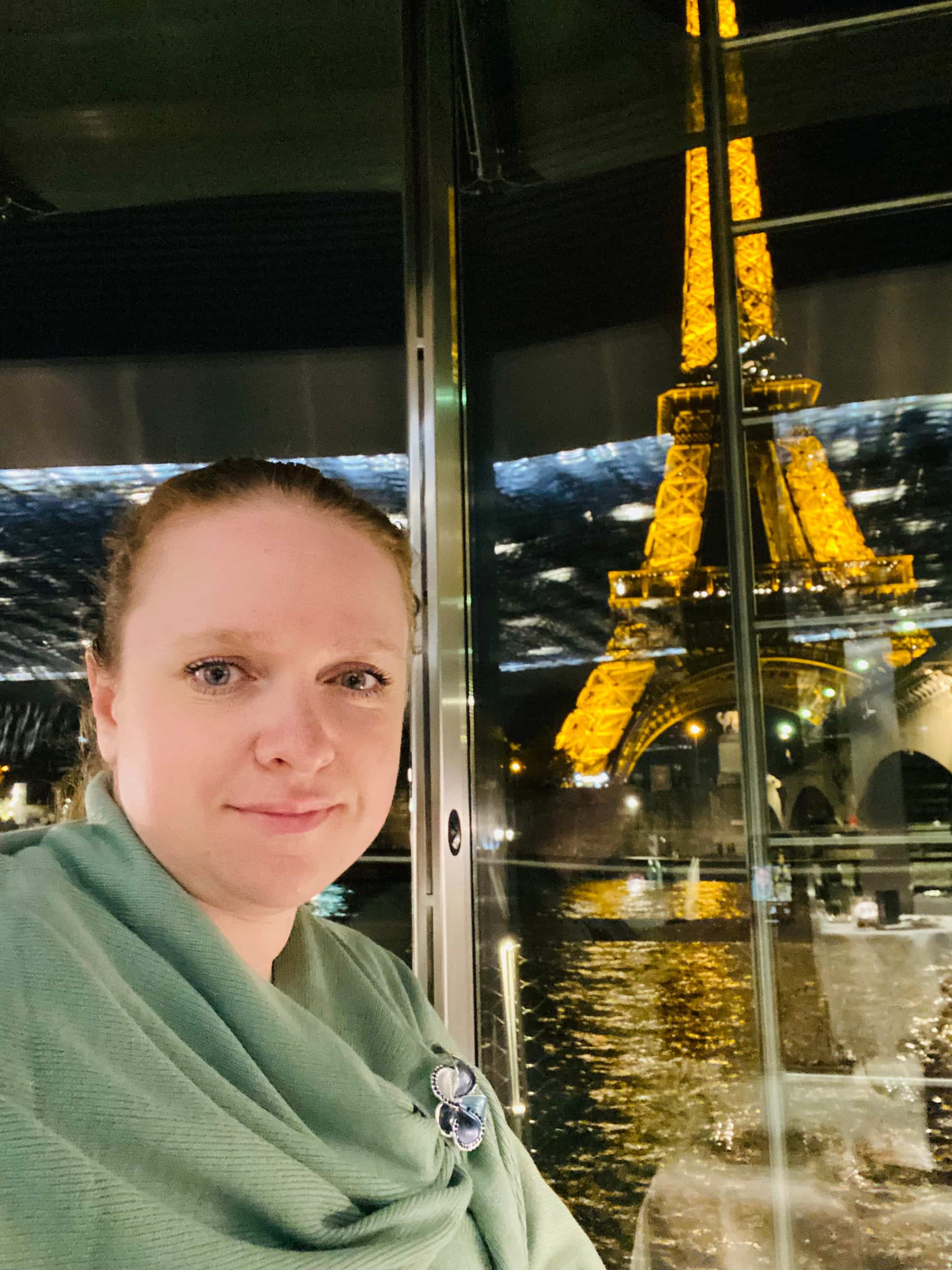 Eiffel Tower illuminated at night, viewed from indoors.