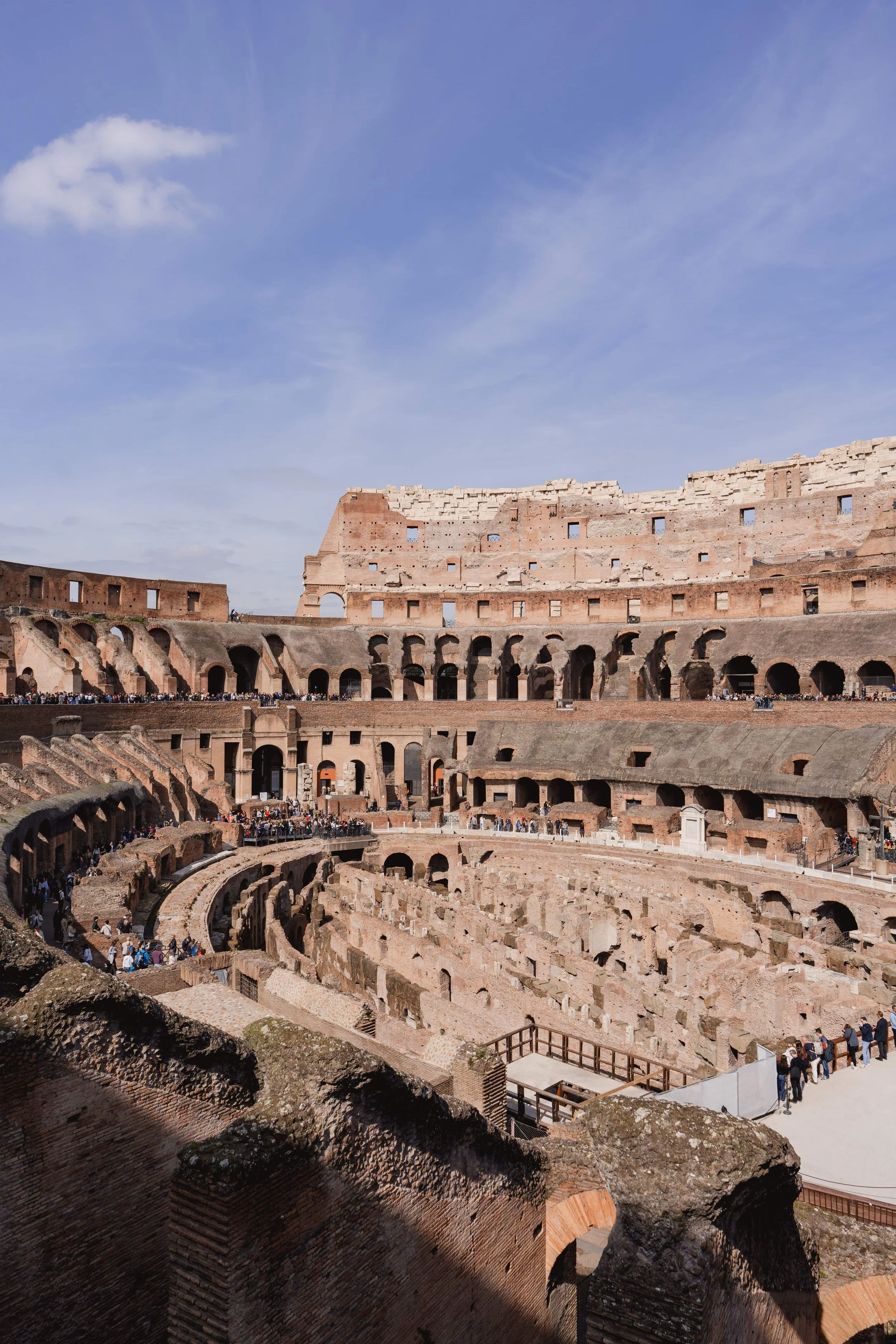 The historic Colosseum in Rome, Italy, stands beneath a clear blue sky, showcasing its iconic ancient arches and impressive stone architecture.