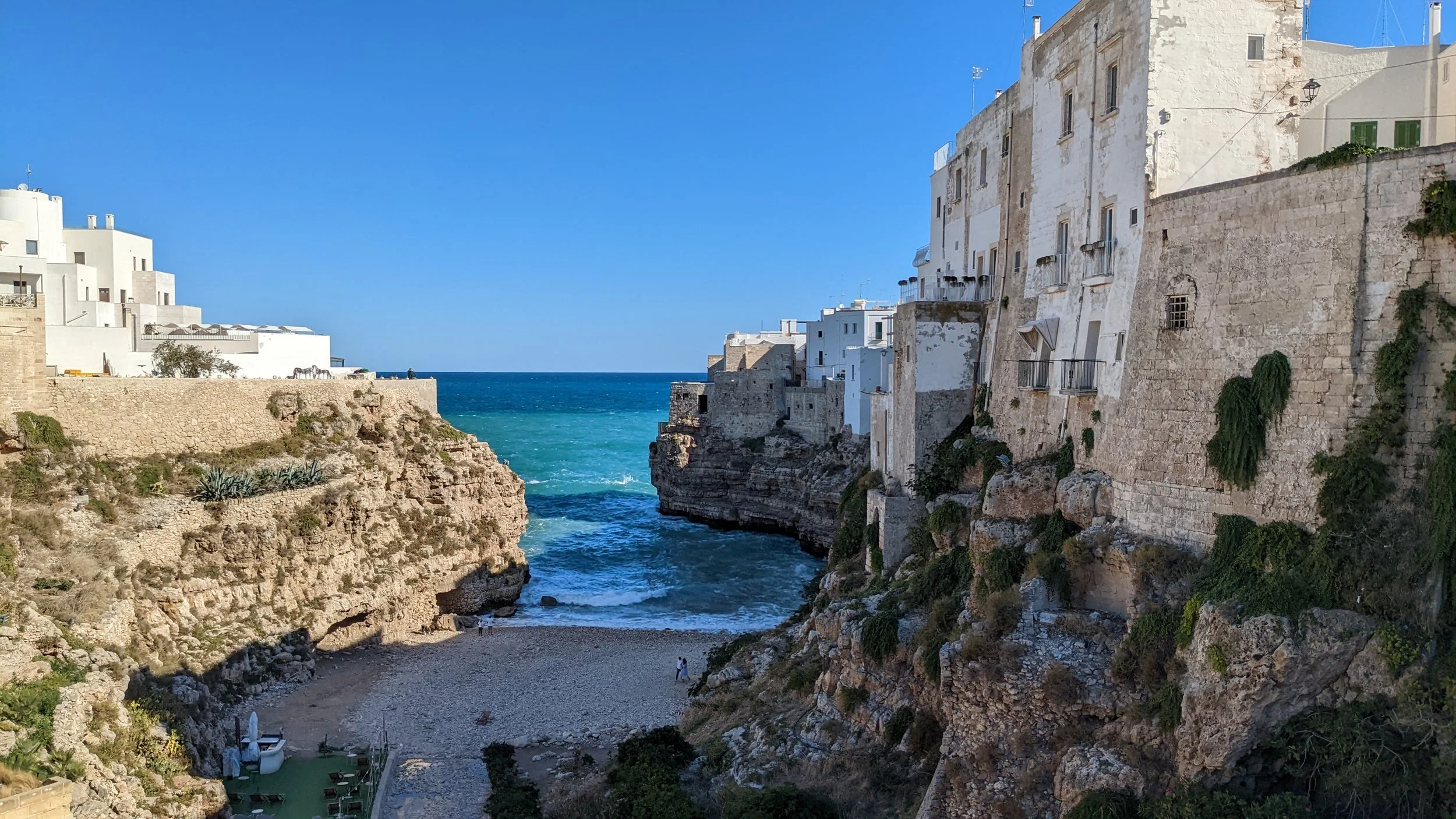 Lama Monachile, a picturesque pebble beach surrounded by limestone cliffs and whitewashed buildings in Polignano a Mare, Puglia, Italy.