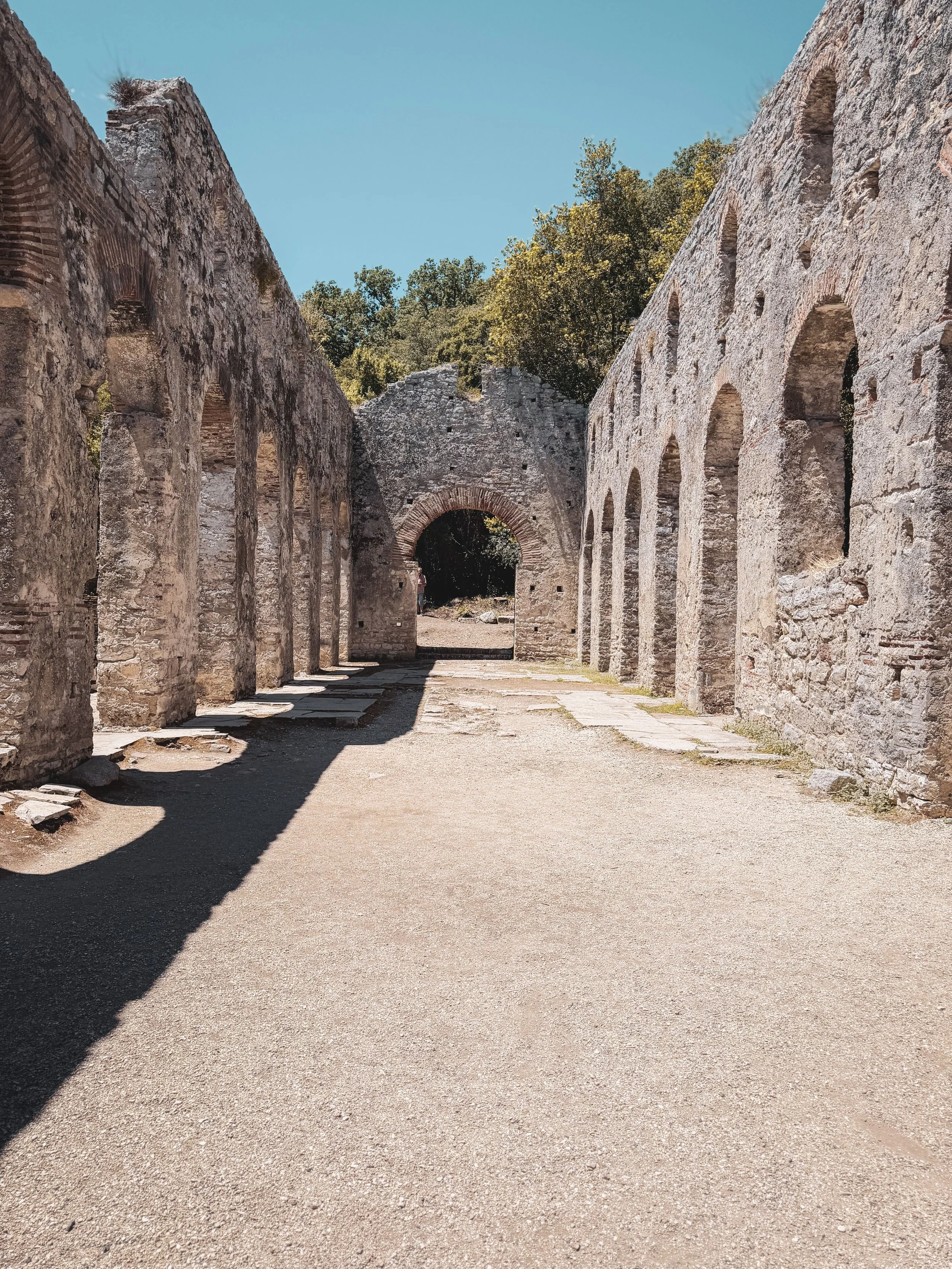 Butrint, Albania, featuring ancient ruins, historic stone architecture, and impressive Roman-era arches surrounded by lush greenery.