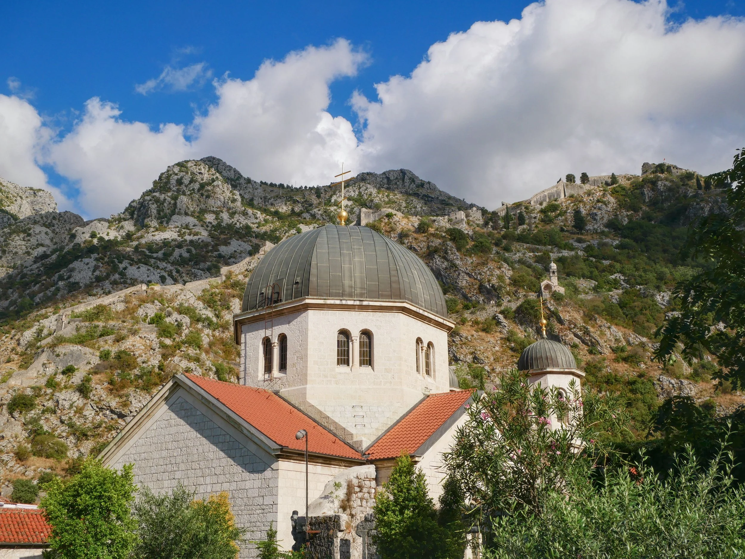 Kotor, Montenegro, featuring a picturesque church nestled against the town’s rugged mountain backdrop.