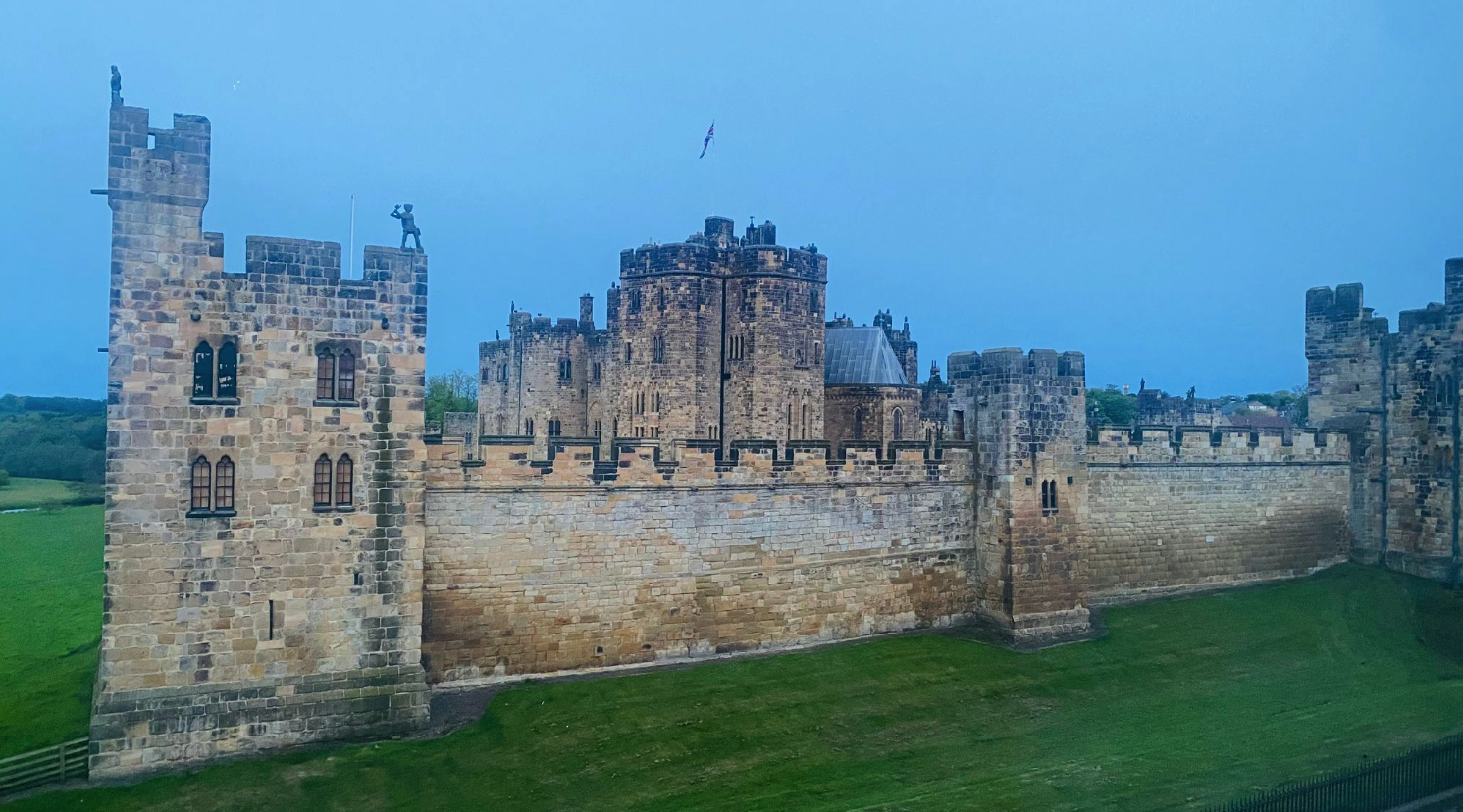 Alnwick Castle, a historic medieval fortress with grand stone architecture and distinctive battlements in Northumberland, England.