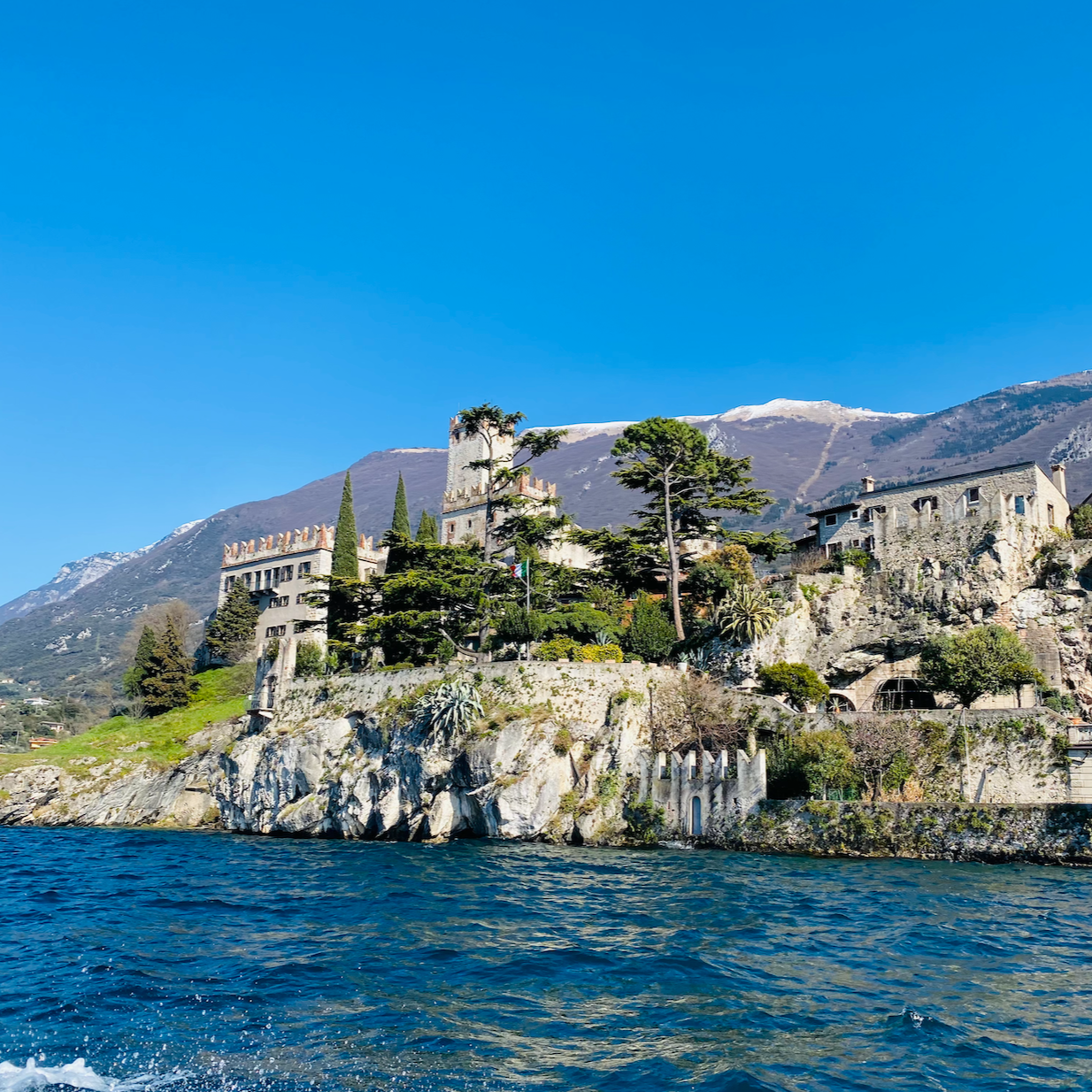 This photo shows the Scaliger Castle of Malcesine (Castello Scaligero di Malcesine), perched on a rocky promontory overlooking Lake Garda in Veneto, Northern Italy.