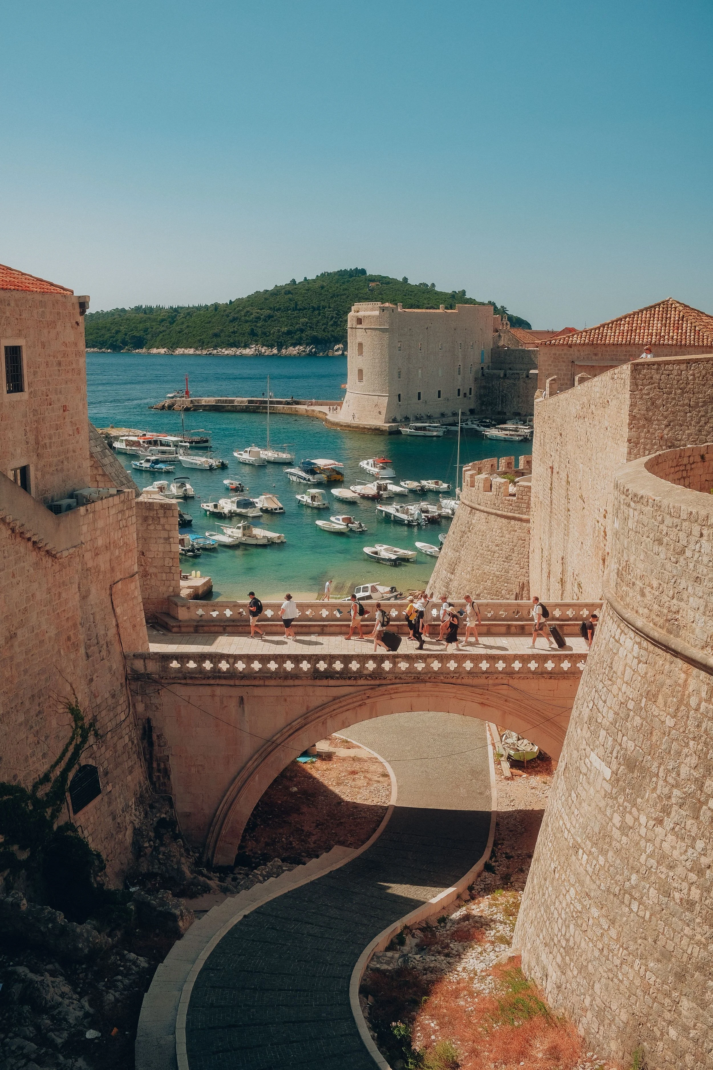 Dubrovnik’s iconic harbor in Croatia, featuring historic medieval walls and vibrant blue Adriatic waters beneath a sunny sky.