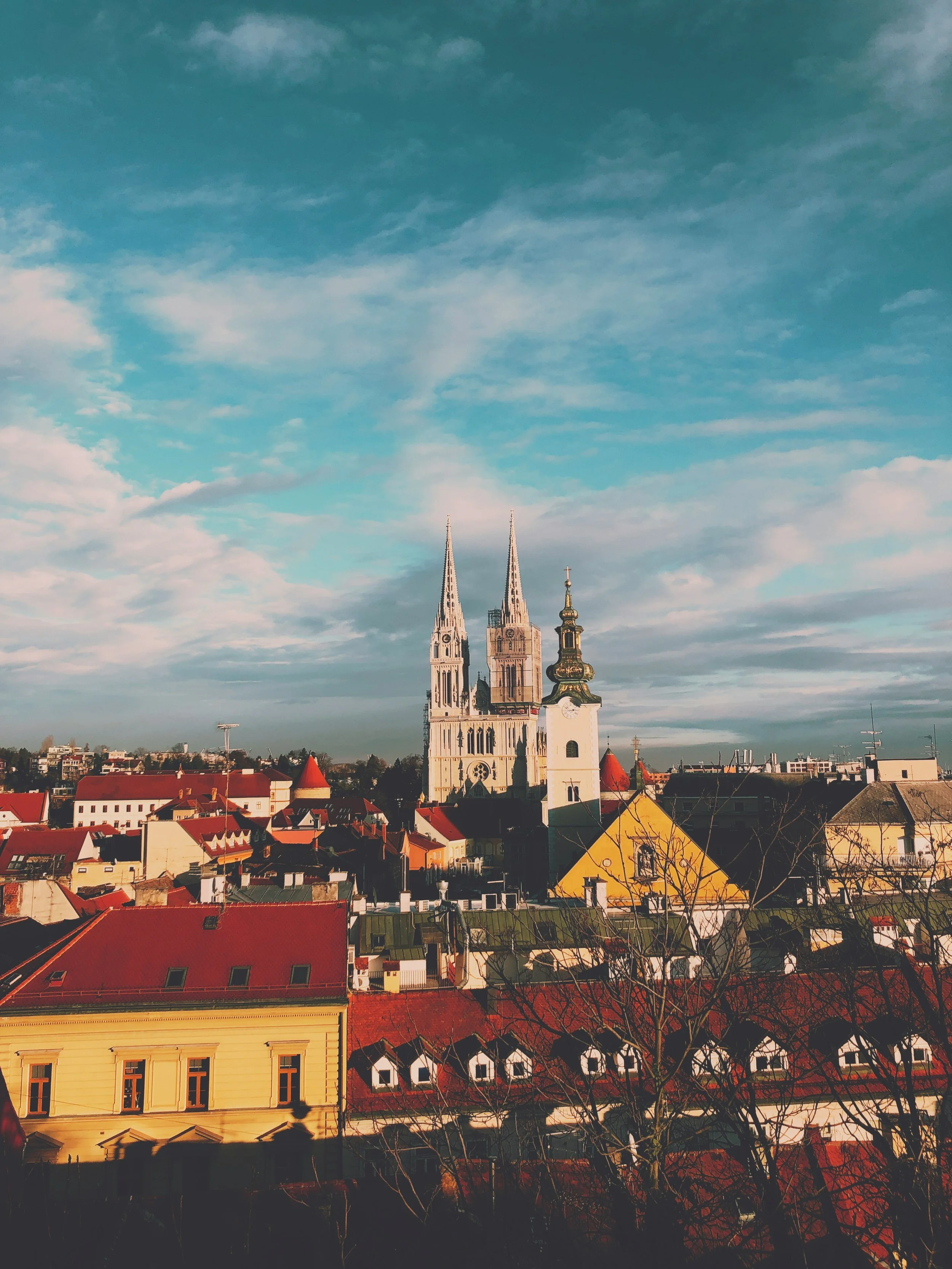 Zagreb, Croatia, featuring historic rooftops and the iconic twin spires of Zagreb Cathedral in the background.
