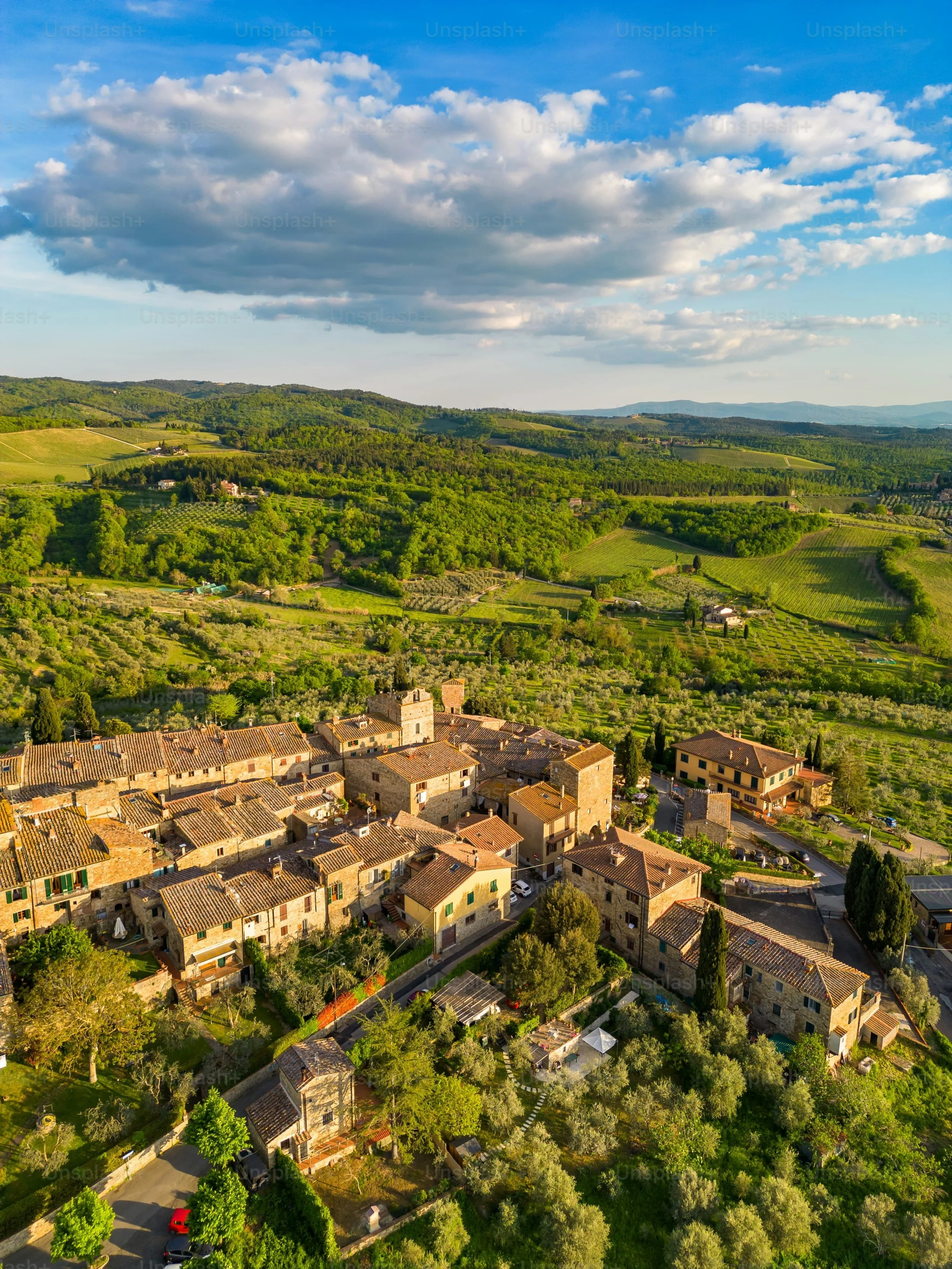 An aerial view of San Donato in Poggio, a medieval hilltop village in Tuscany’s Chianti region, Italy, featuring historic stone buildings, terracotta rooftops, and the surrounding rolling countryside.