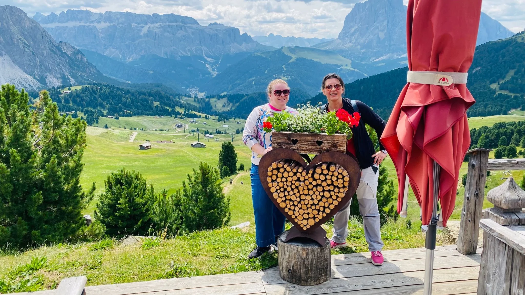 A heart-shaped wooden planter in Val Gardena, South Tyrol, Italy, with the dramatic limestone peaks of the Dolomites in the background.