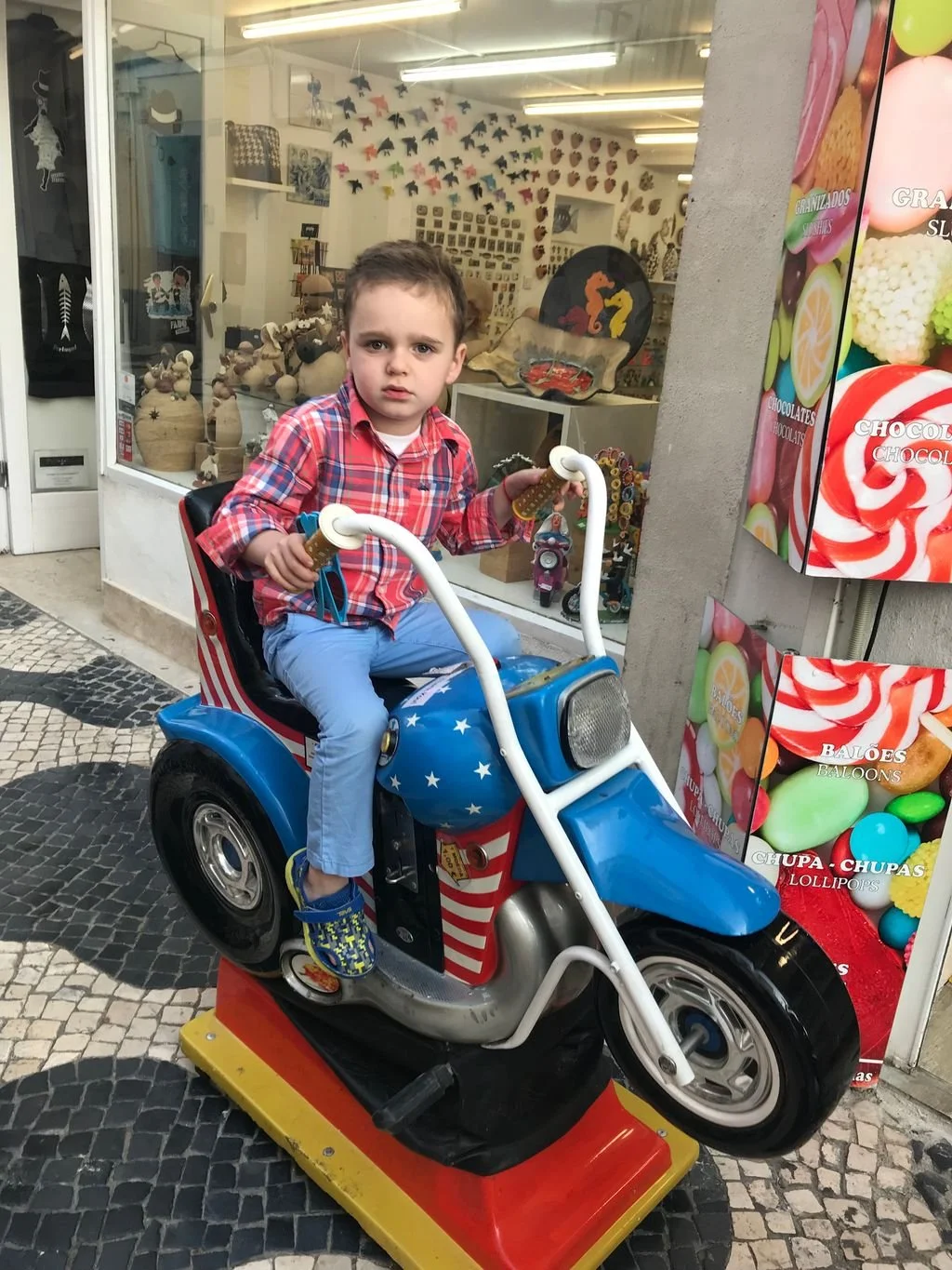 Vintage coin-operated motorcycle kiddie ride outside a shop in Portugal.
