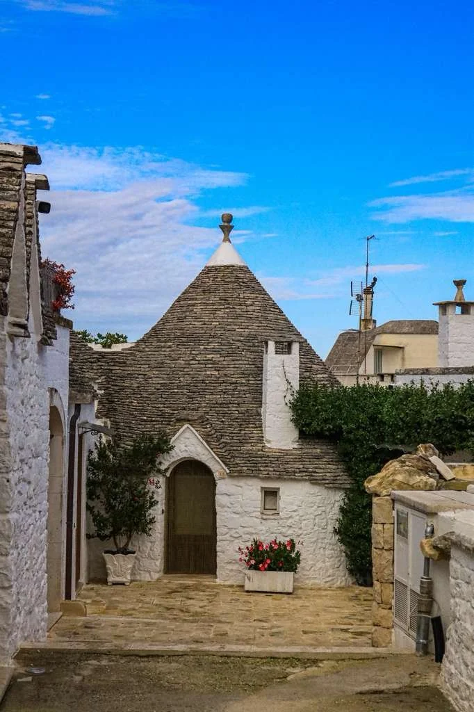 Traditional trullo house with whitewashed stone walls and a distinctive conical limestone roof in Alberobello, Puglia, Italy.