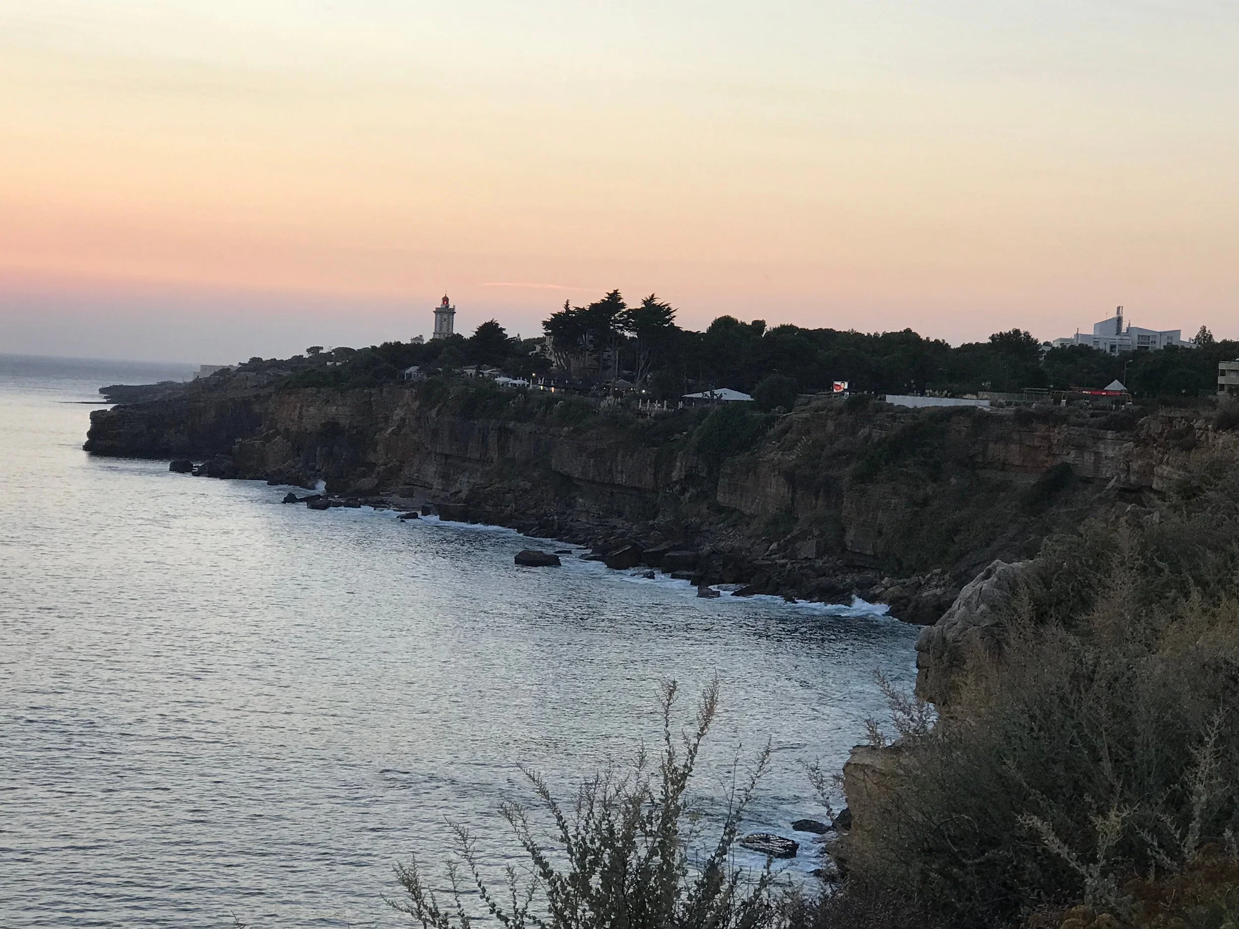 Rugged Atlantic coastline near Farol da Guia, Cascais, Portugal, at dusk.