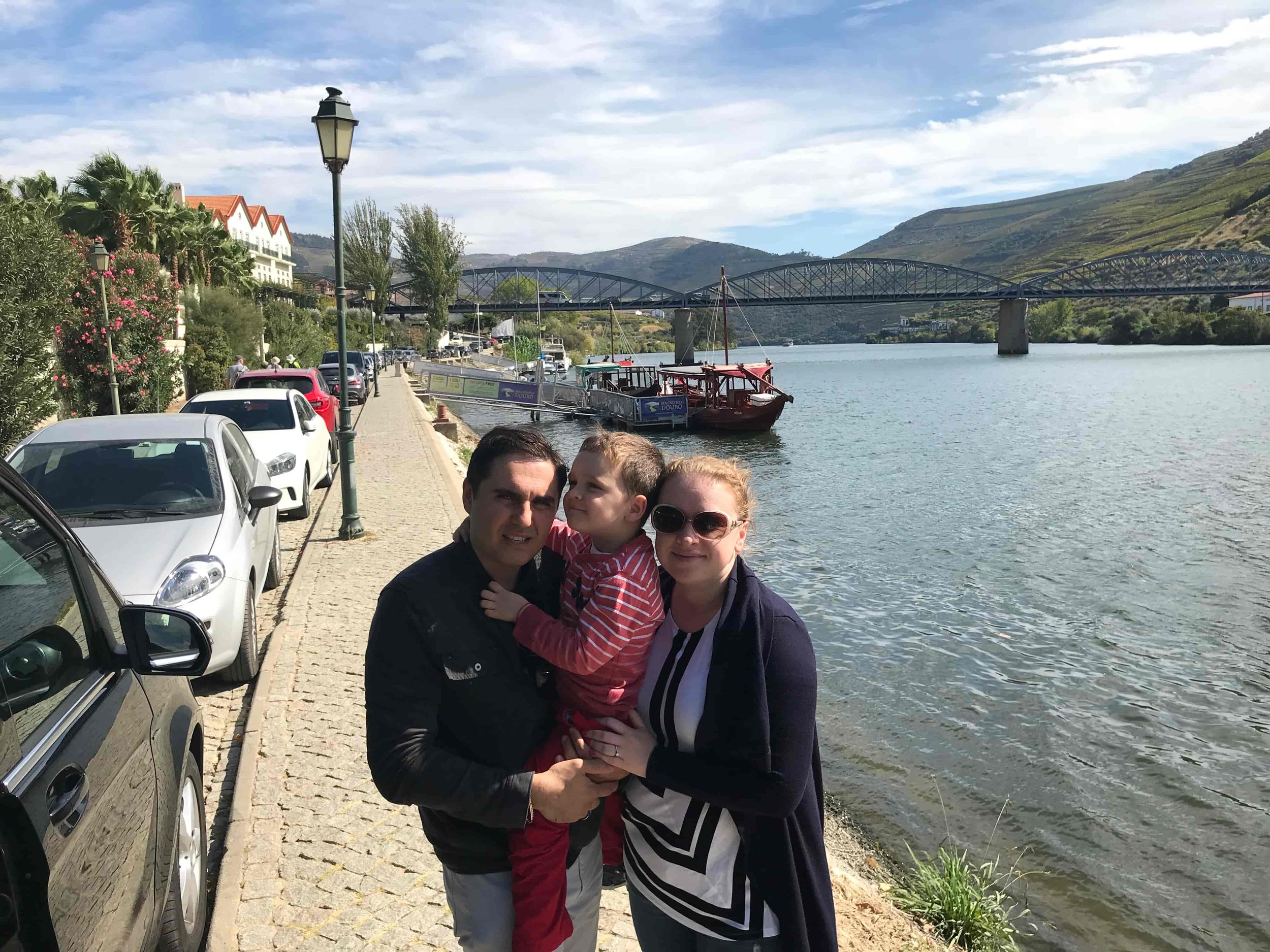 Scenic Douro River waterfront in Pinhão, Portugal, with traditional Rabelo boats and bridges.