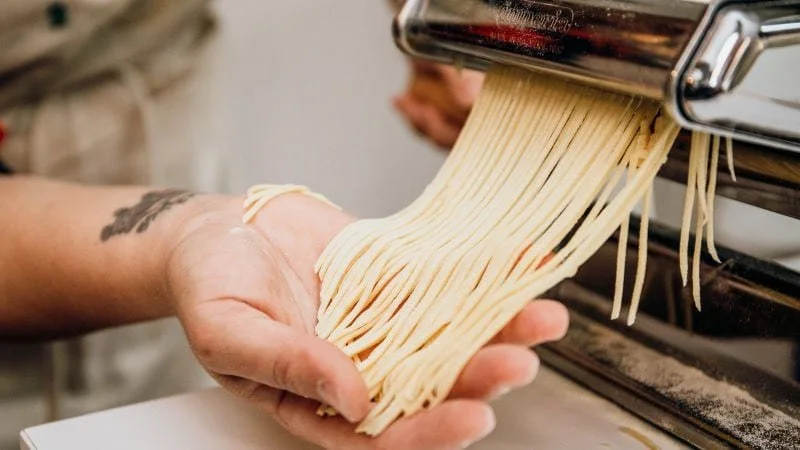 A hand holds handmade pasta in Italy.