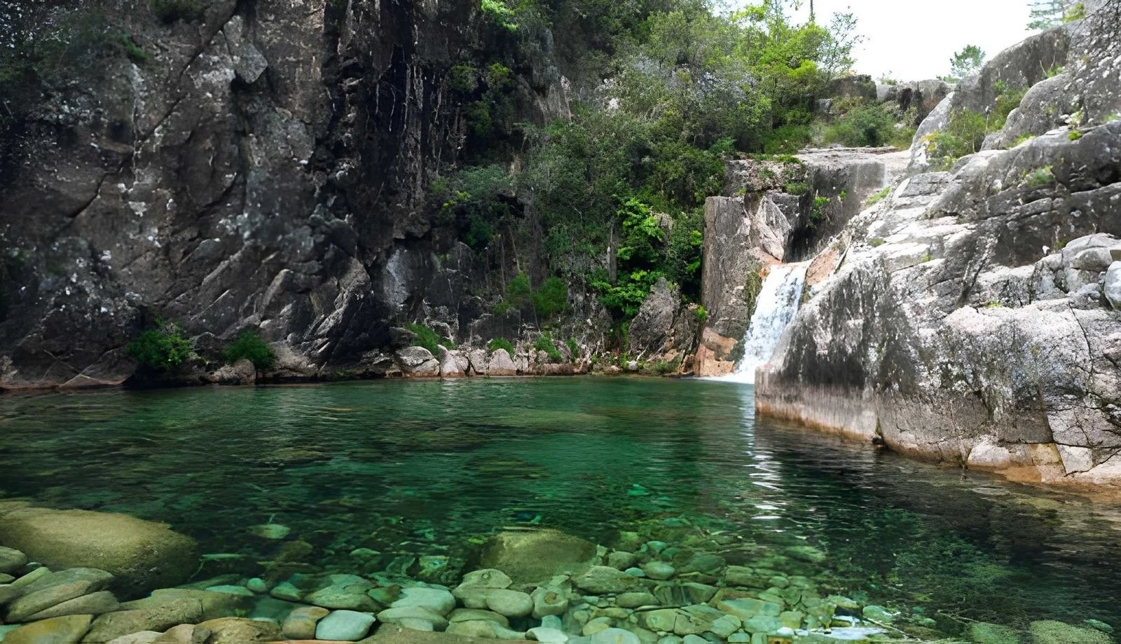 Cascata da Portela do Homem, a scenic waterfall with a turquoise pool in Peneda-Gerês National Park, Portugal.