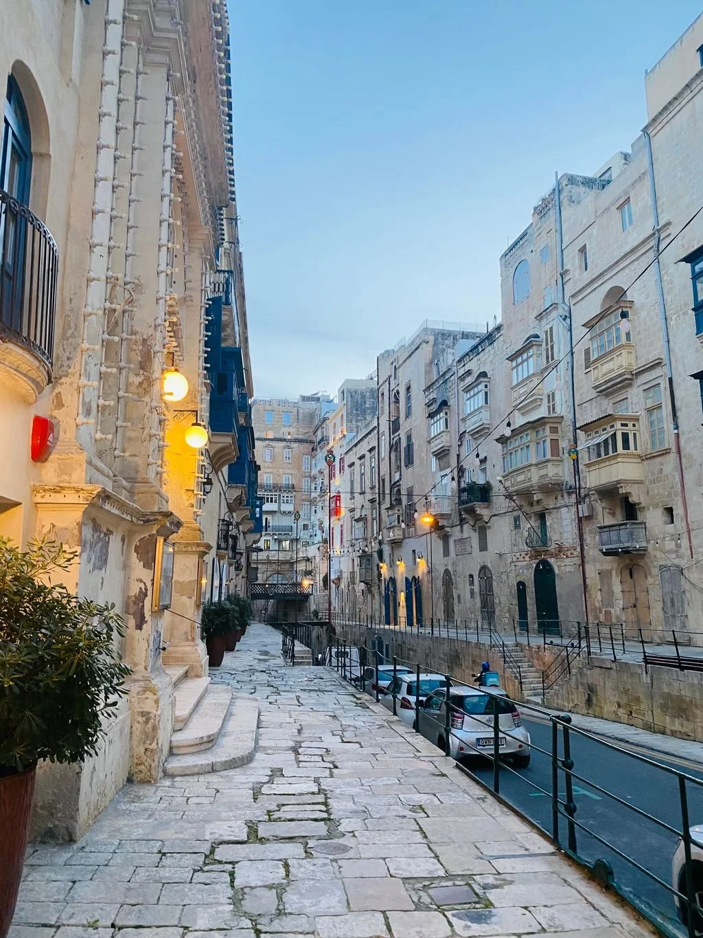 Historic street in Valletta Malta featuring traditional limestone buildings and colorful wooden balconies at dusk