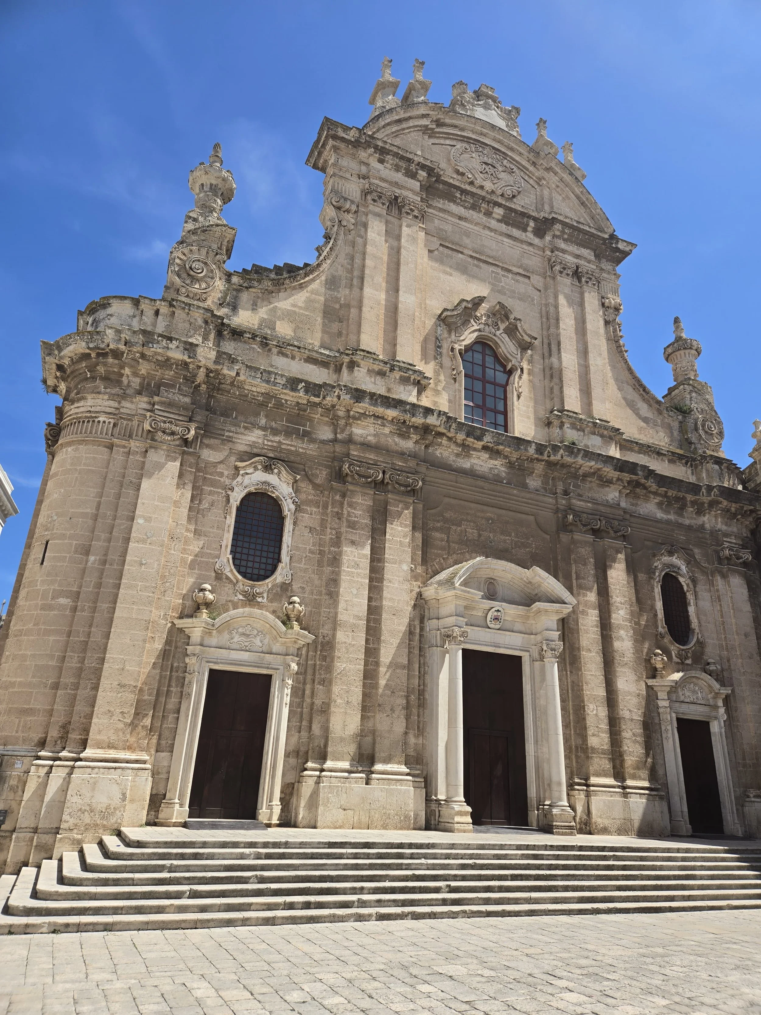 Monopoli Cathedral, featuring an ornate Baroque limestone facade and grand stone steps in Monopoli, Puglia, Italy.