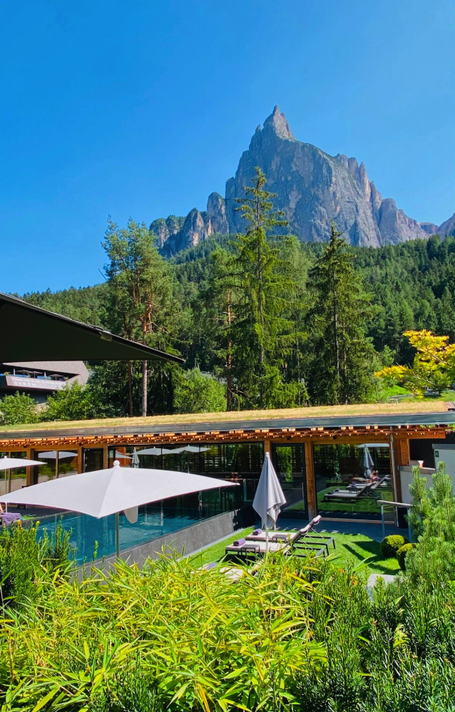 The award-winning spa design of the Sensoria Dolomites hotel in Seis am Schlern, Italy, specifically highlighting its panoramic outdoor pool with direct views of the Schlern mountain.