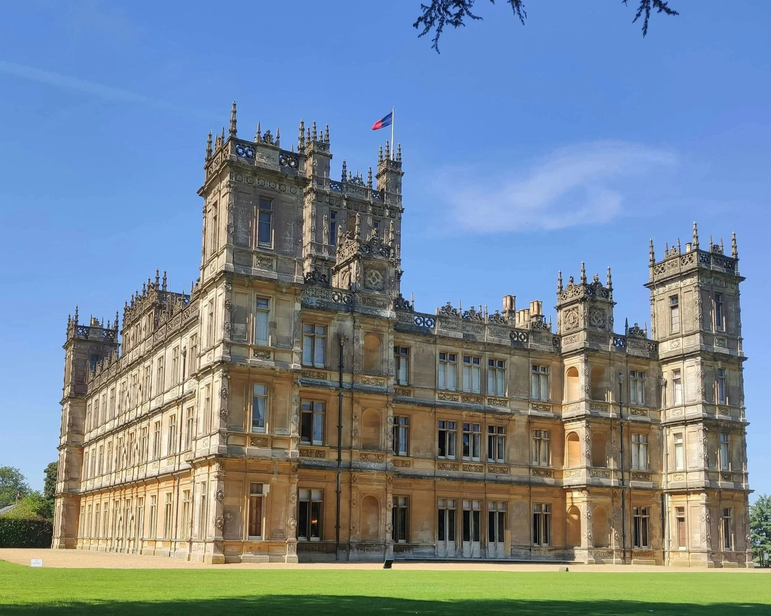 Highclere Castle, a grand Victorian country house surrounded by picturesque parkland in Hampshire, England.