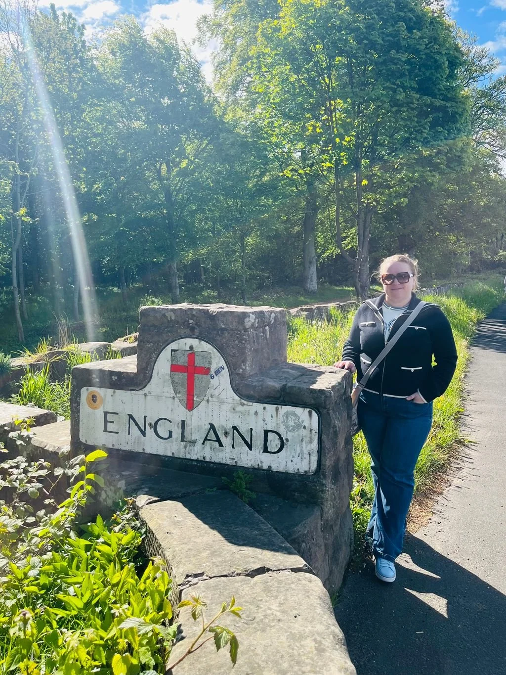 England-Scotland border at Coldstream Bridge, with a stone border marker and wooded landscape.