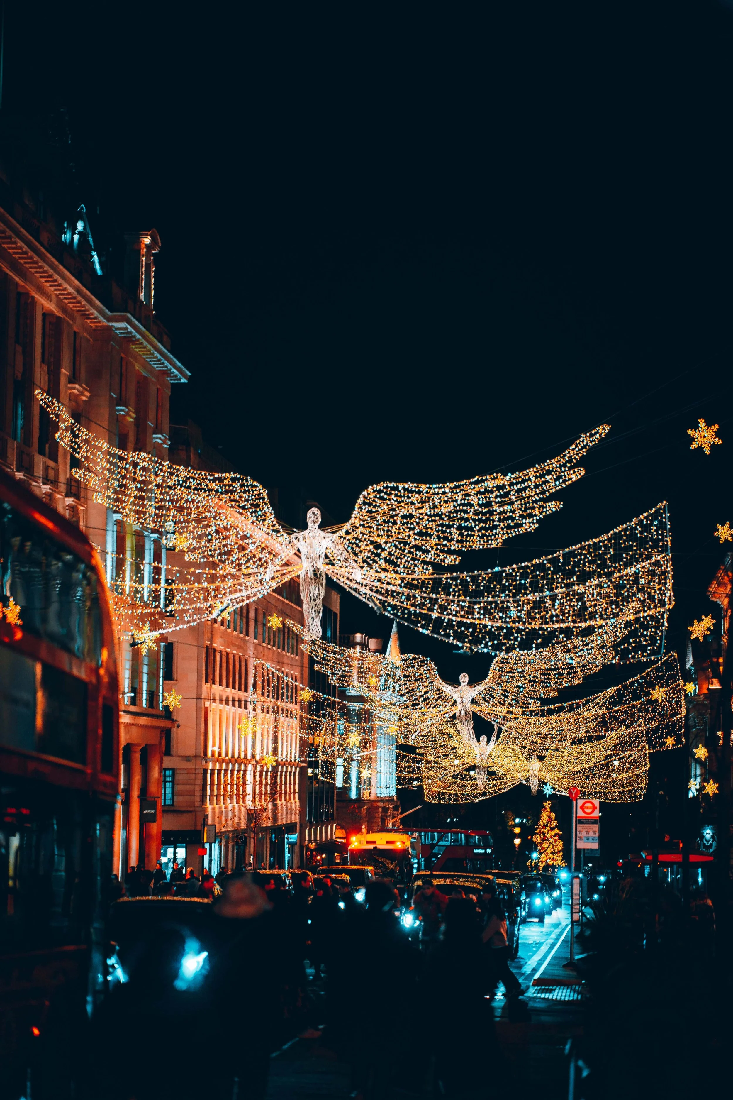 Festive angel light decorations illuminating a London street at night, creating a magical atmosphere.