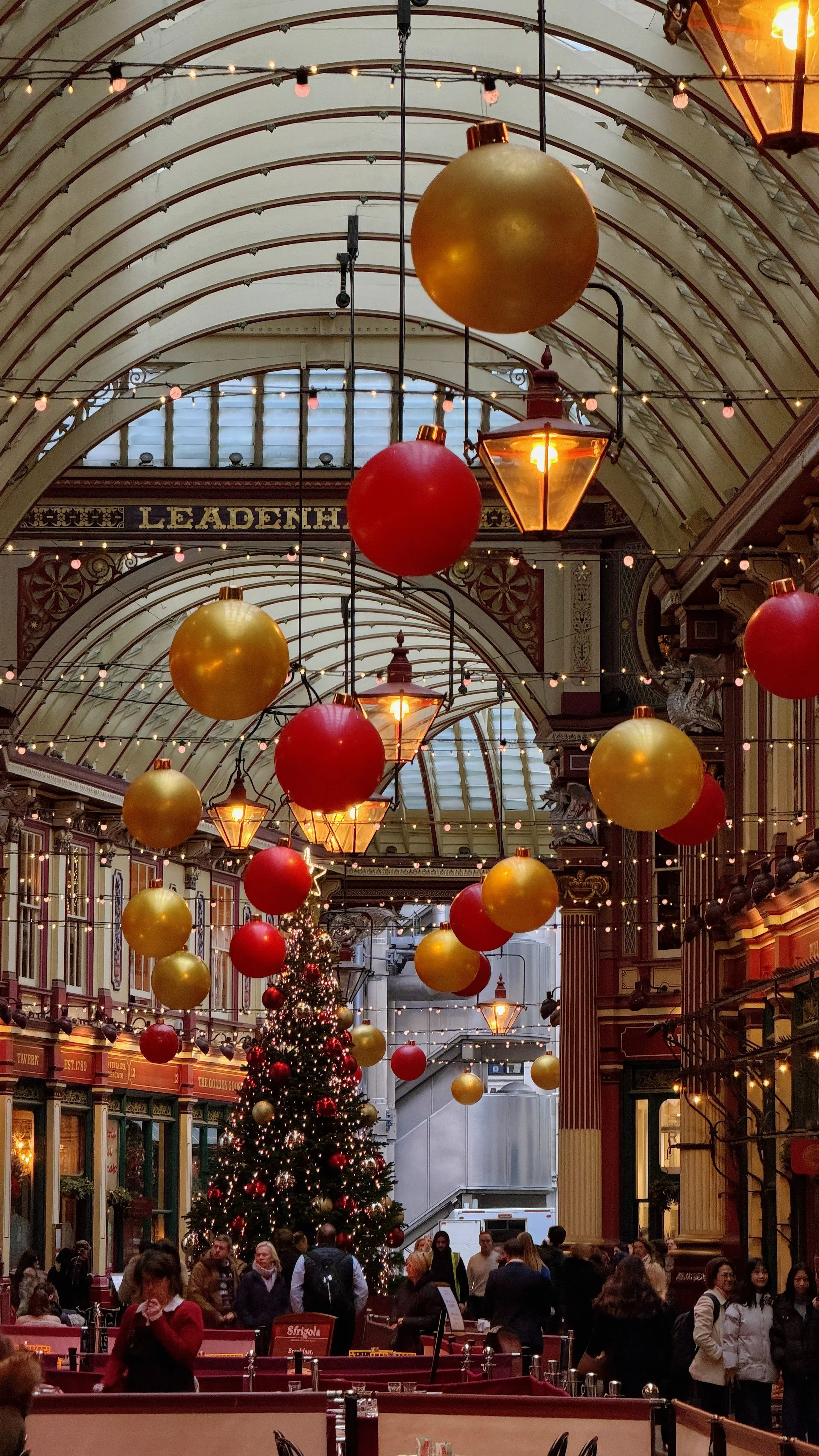 Leadenhall Market in London, England, adorned with colorful Christmas decorations and a festive tree.