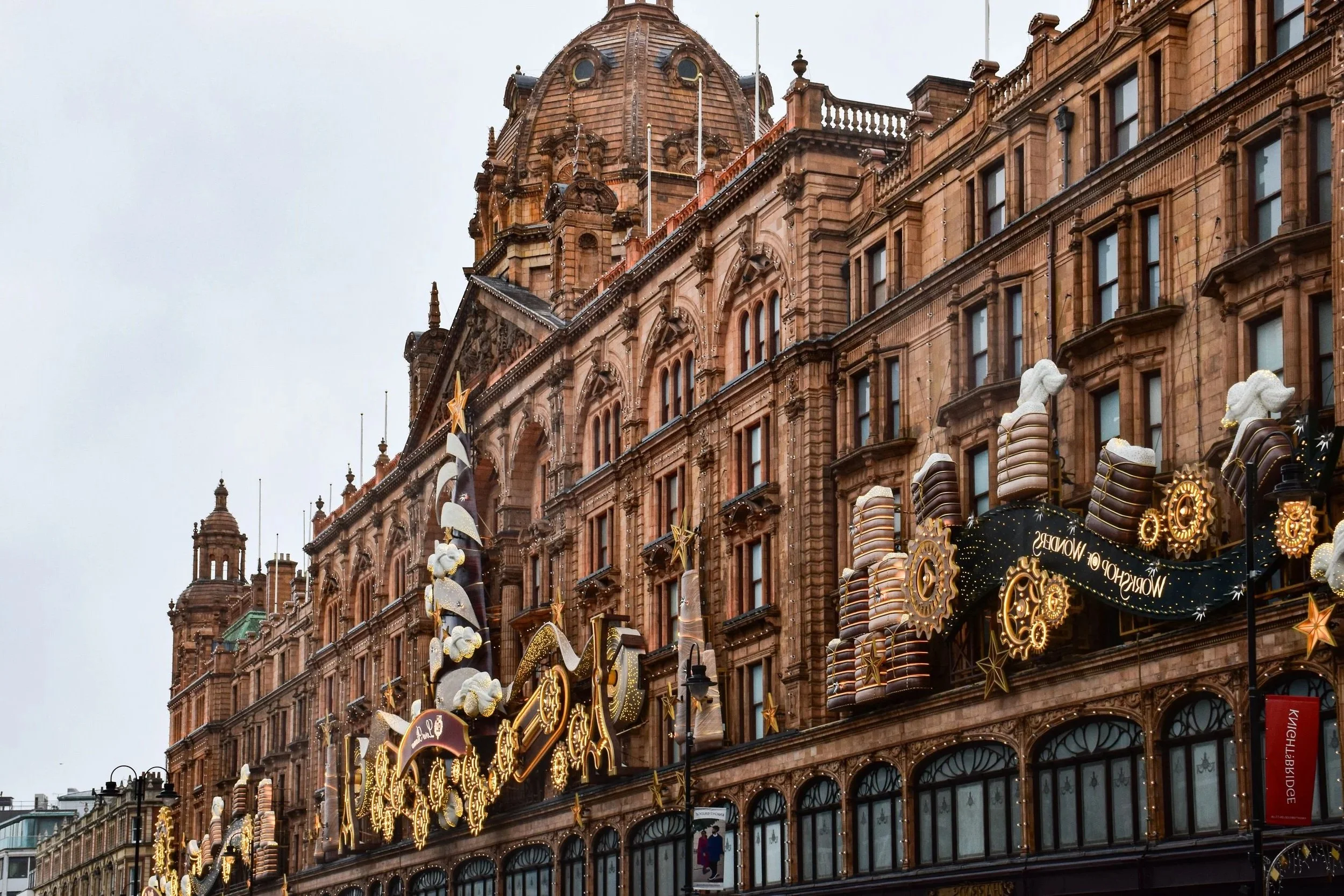 Harrods in Knightsbridge, London, with its iconic facade adorned with festive holiday decorations and lights.