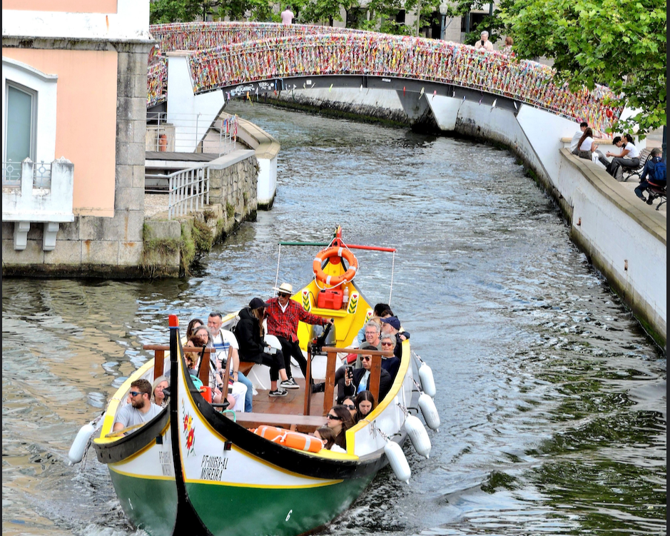 Colorful boat navigating a scenic canal in Aveiro, Portugal.