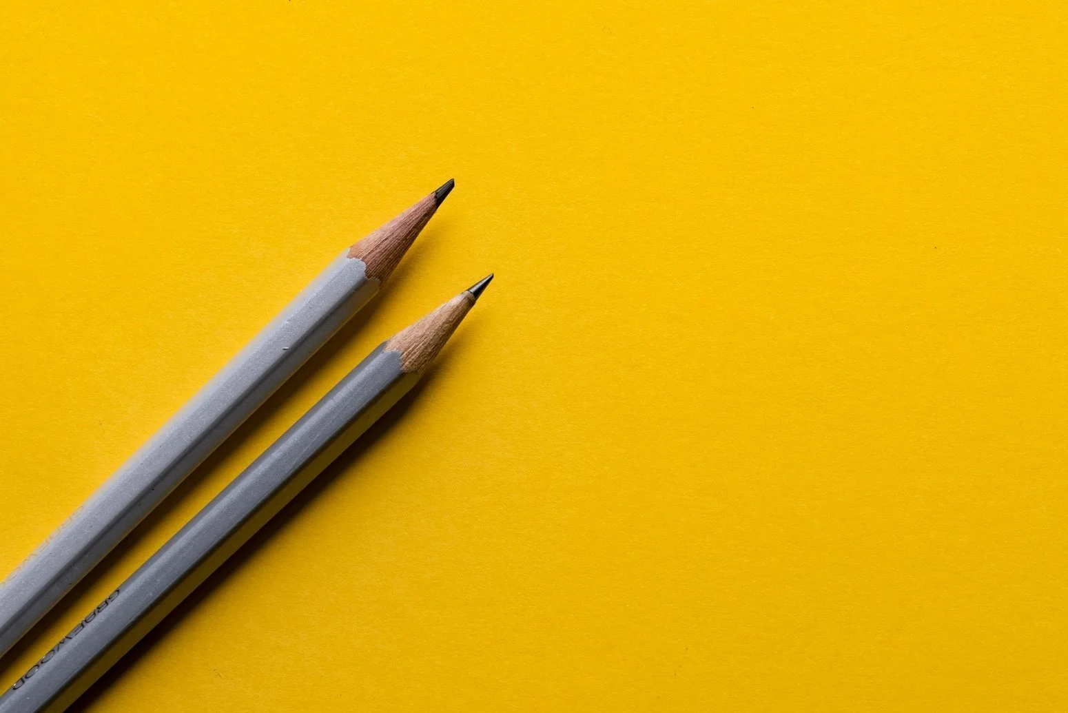 Yellow background with a logo that says 'Association for Play Therapy' in blue and has a red icon of a person with raised arms and a smaller figure, along with two gray pencils resting on the surface.
