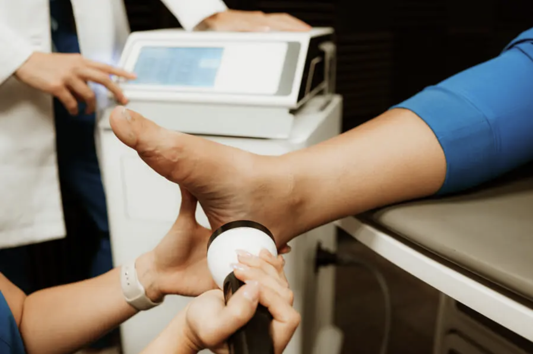 Medical professional performing ultrasound therapy on patient's elbow in clinical setting.