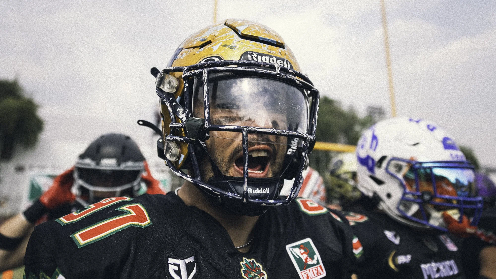 Football players wearing helmets and black jerseys, with one player shouting.
