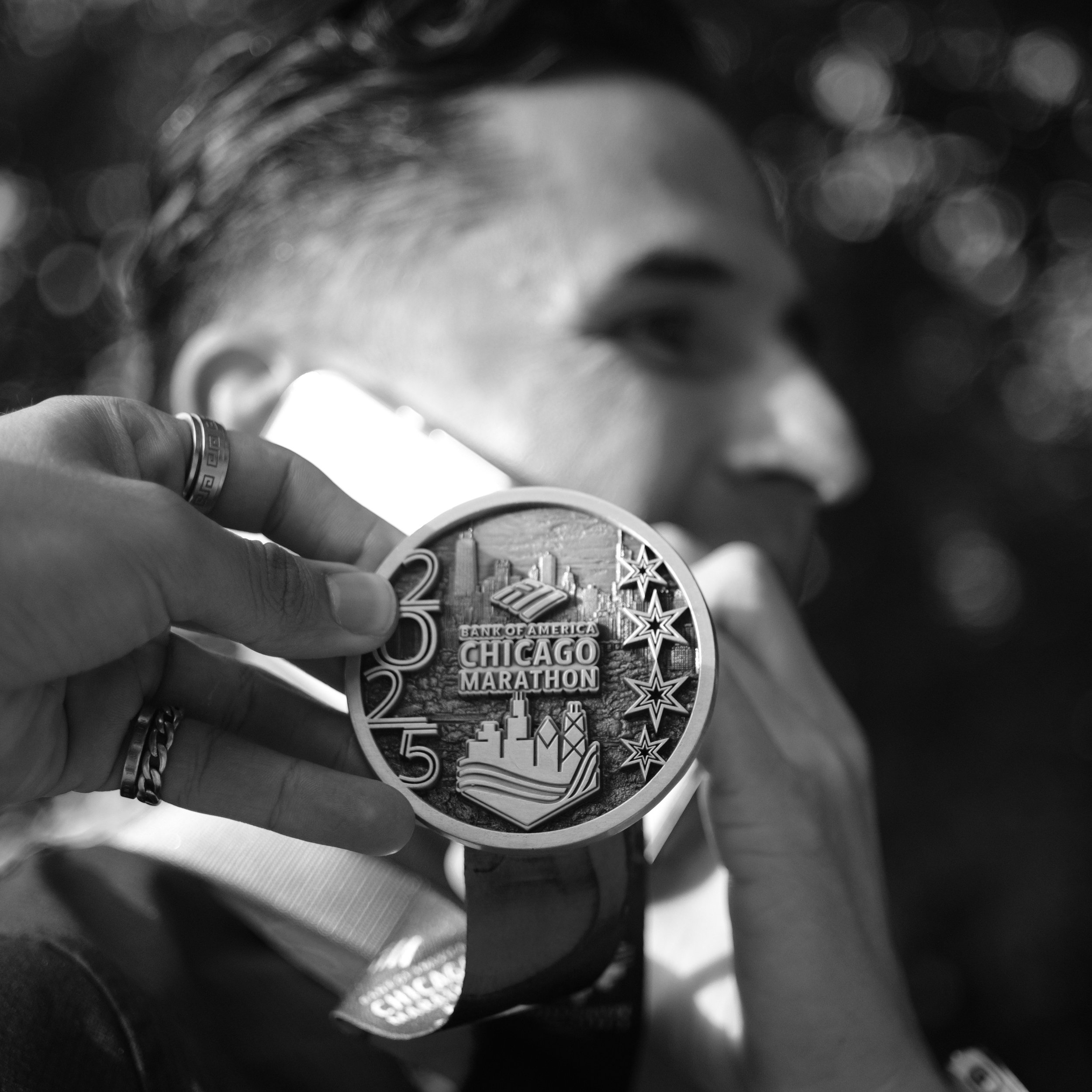 A person holding finisher medal for the Chicago Marathon in black and white