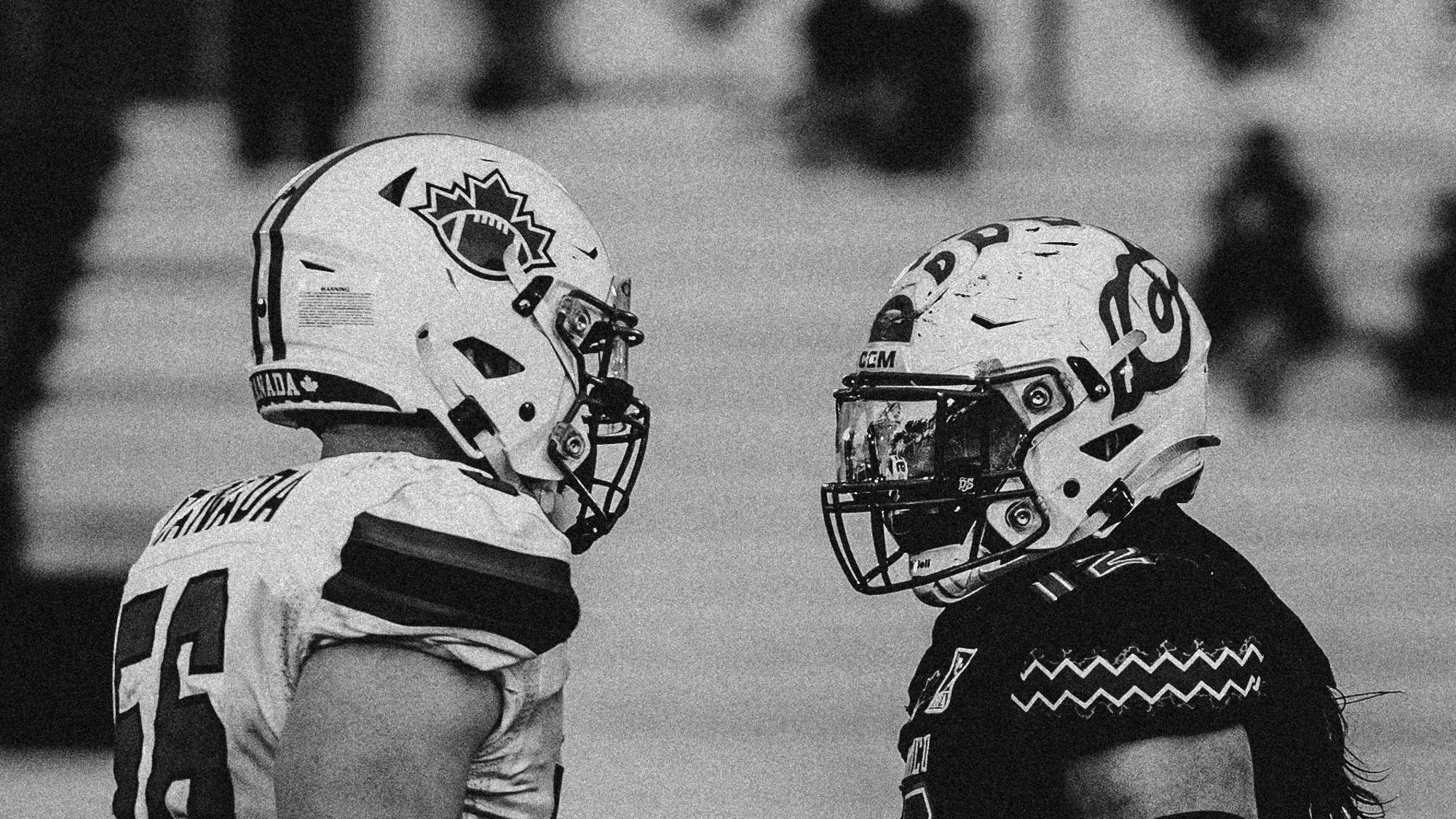 Two football players wearing helmets and uniforms facing each other during a game.
