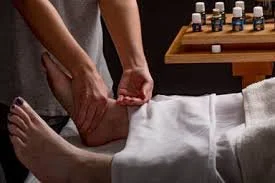 A person receiving a massage on their ankle from a massage therapist in a spa or massage room.