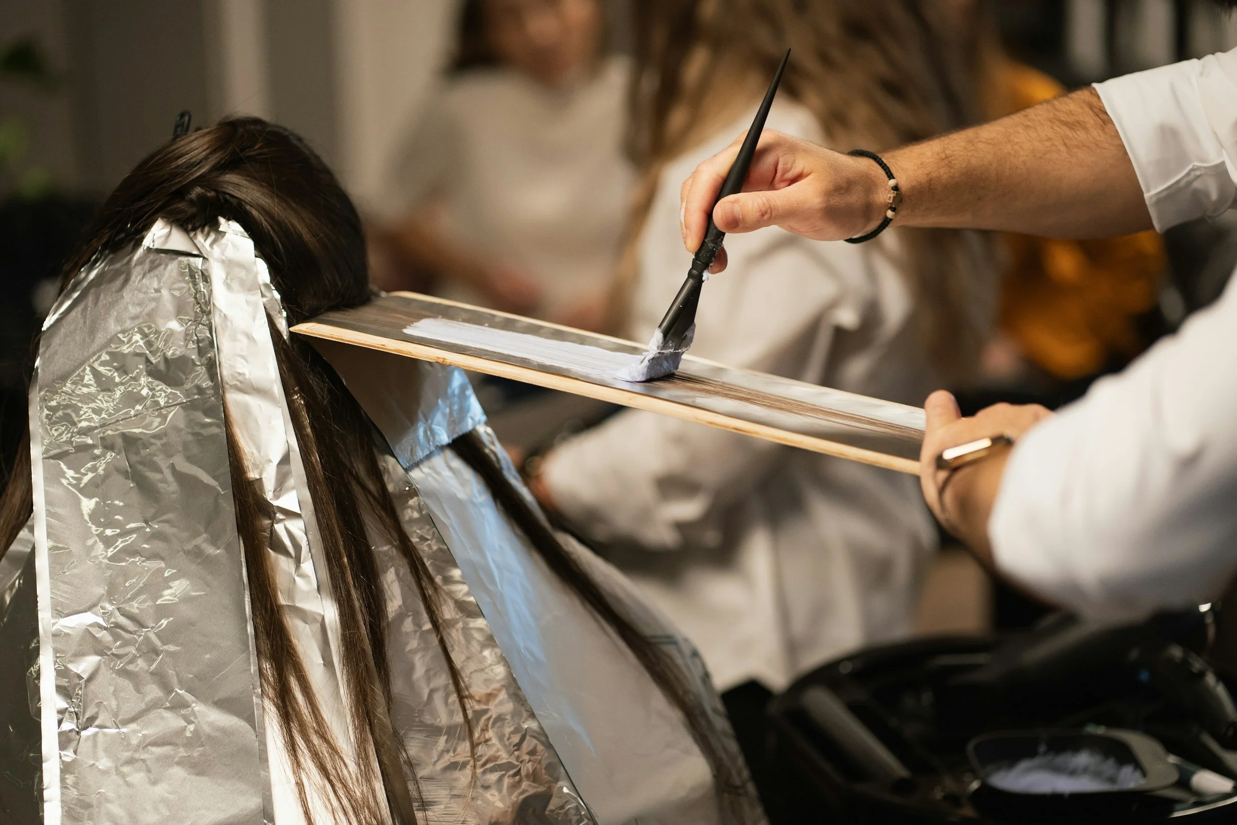Hair color being applied in salon, representing consistent client experience and behind-the-scenes content.