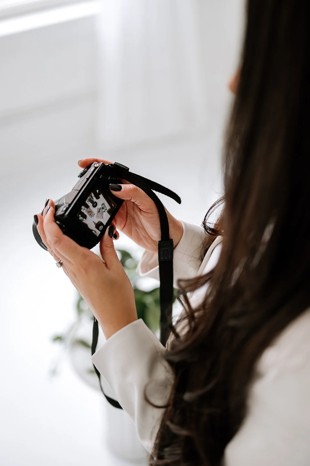 Marketing studio owner holding a camera and reviewing photos, representing content creation and creative direction.